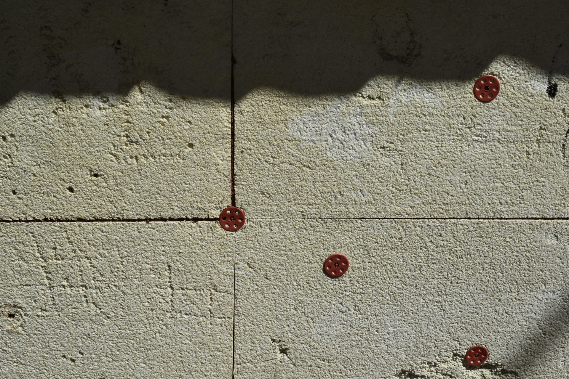 Textured wall with small red circular fasteners