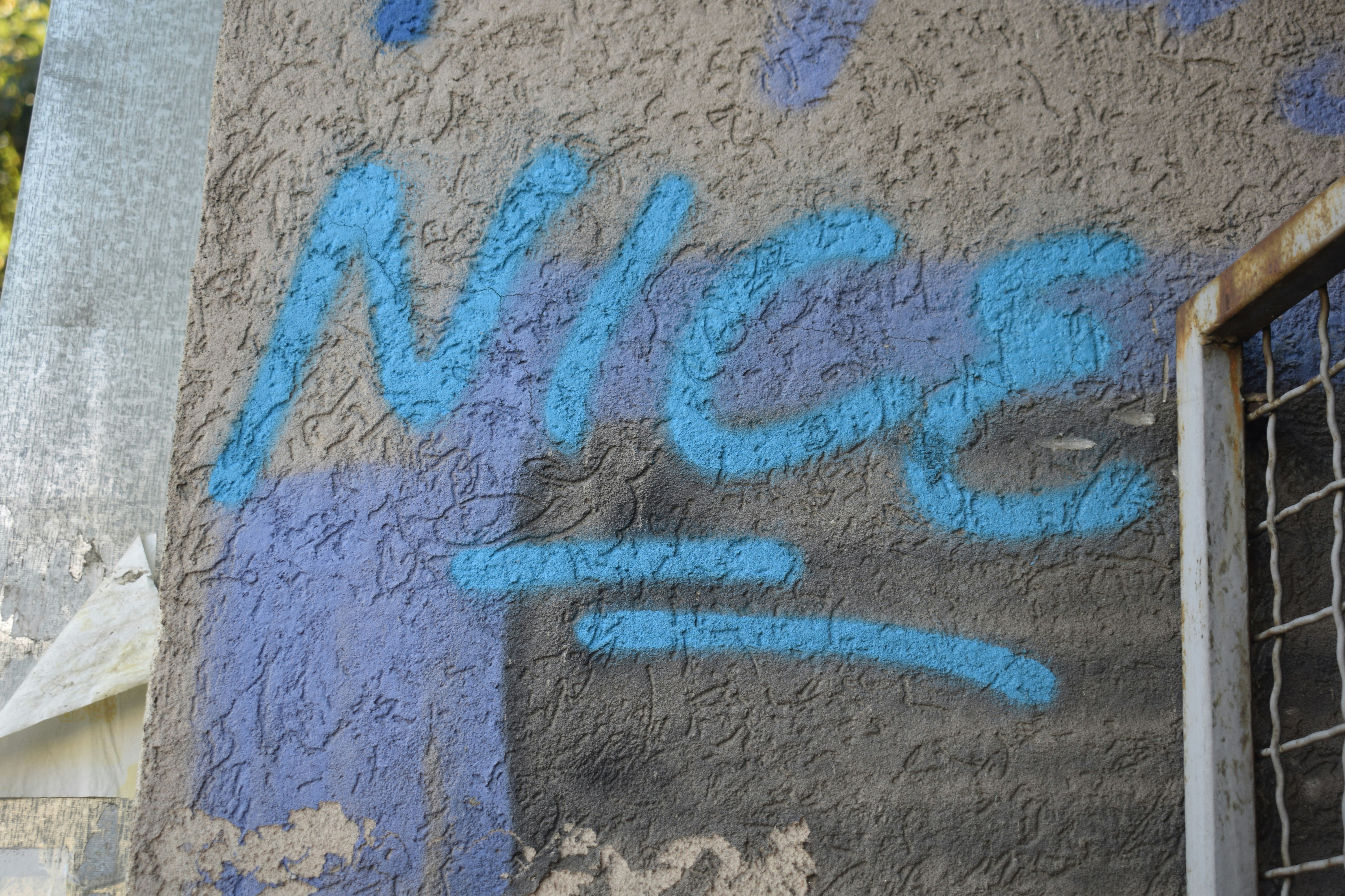 Blaues Graffiti-Tag an einer strukturierten Wand