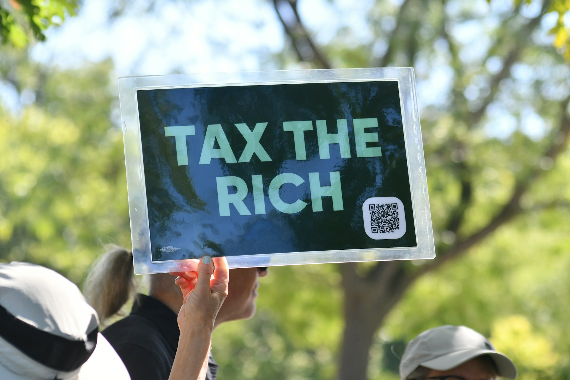 Person holds sign that says "tax the rich"