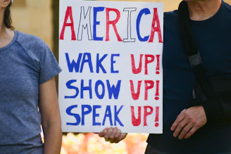 People holding a sign that says america wake up!