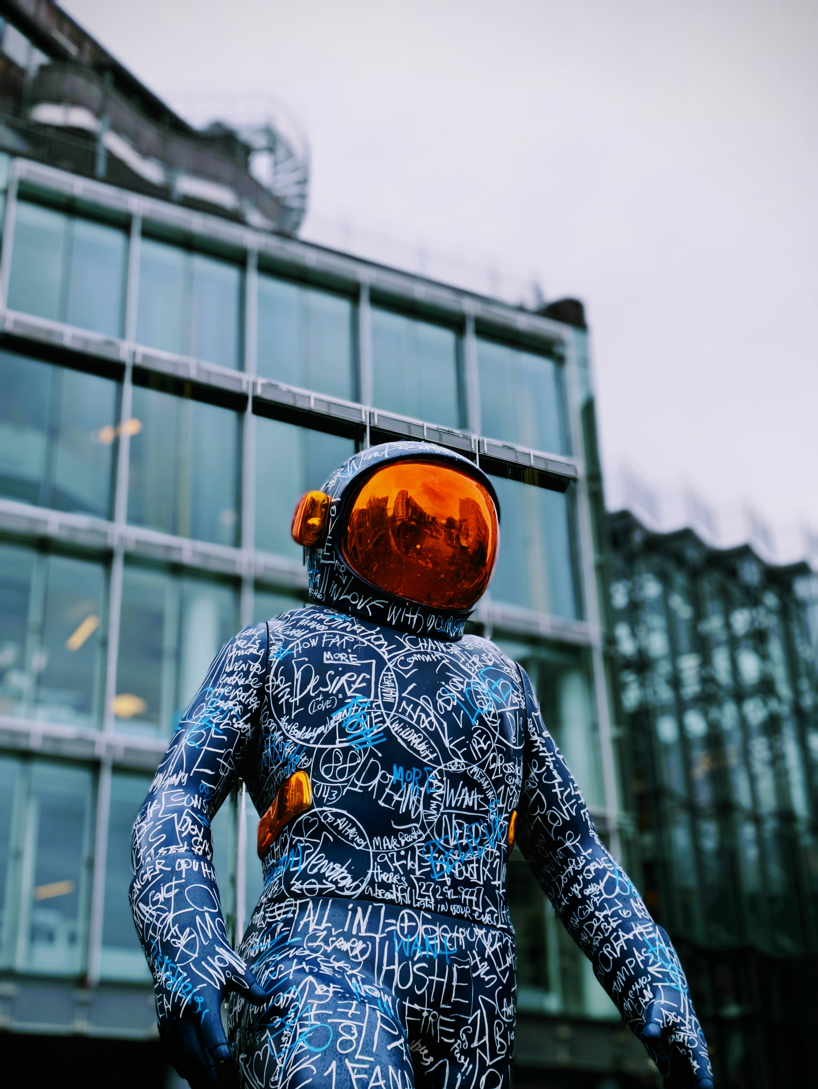 Astronaut statue with reflective orange helmet and graffiti suit.