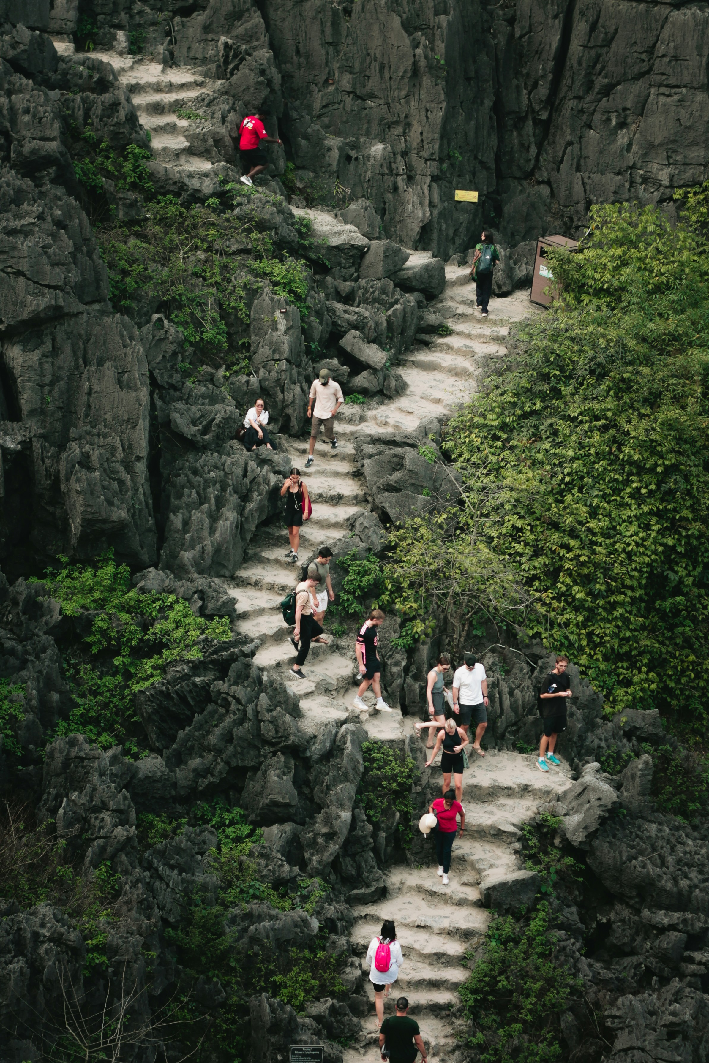 바위가 많은 산비탈에서 돌계단을 오르는 사람들.