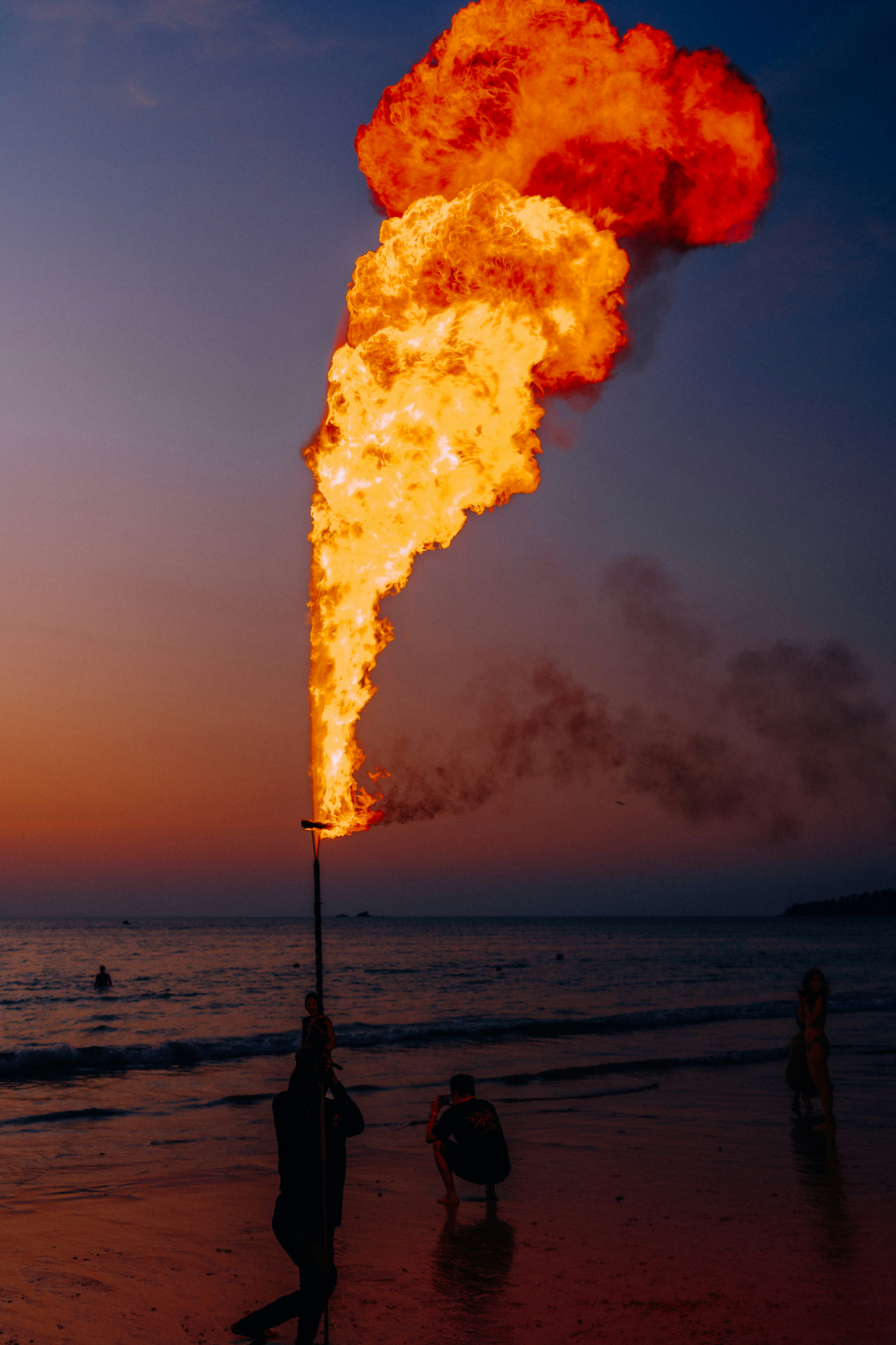 Person breathing fire on a beach at sunset