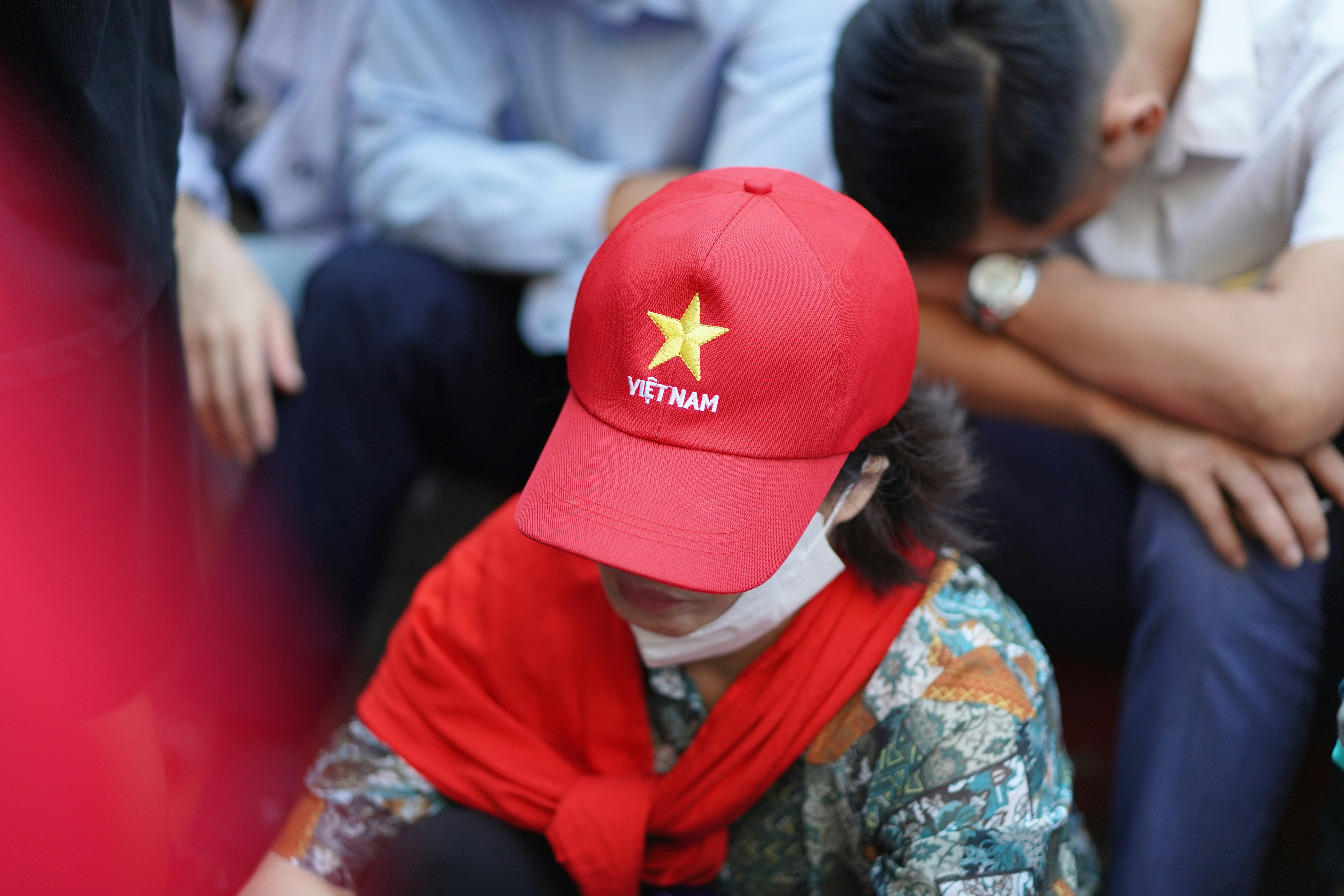 Person wearing a red cap with vietnam flag emblem.