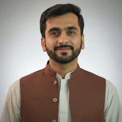 A man in traditional clothing smiles at the camera