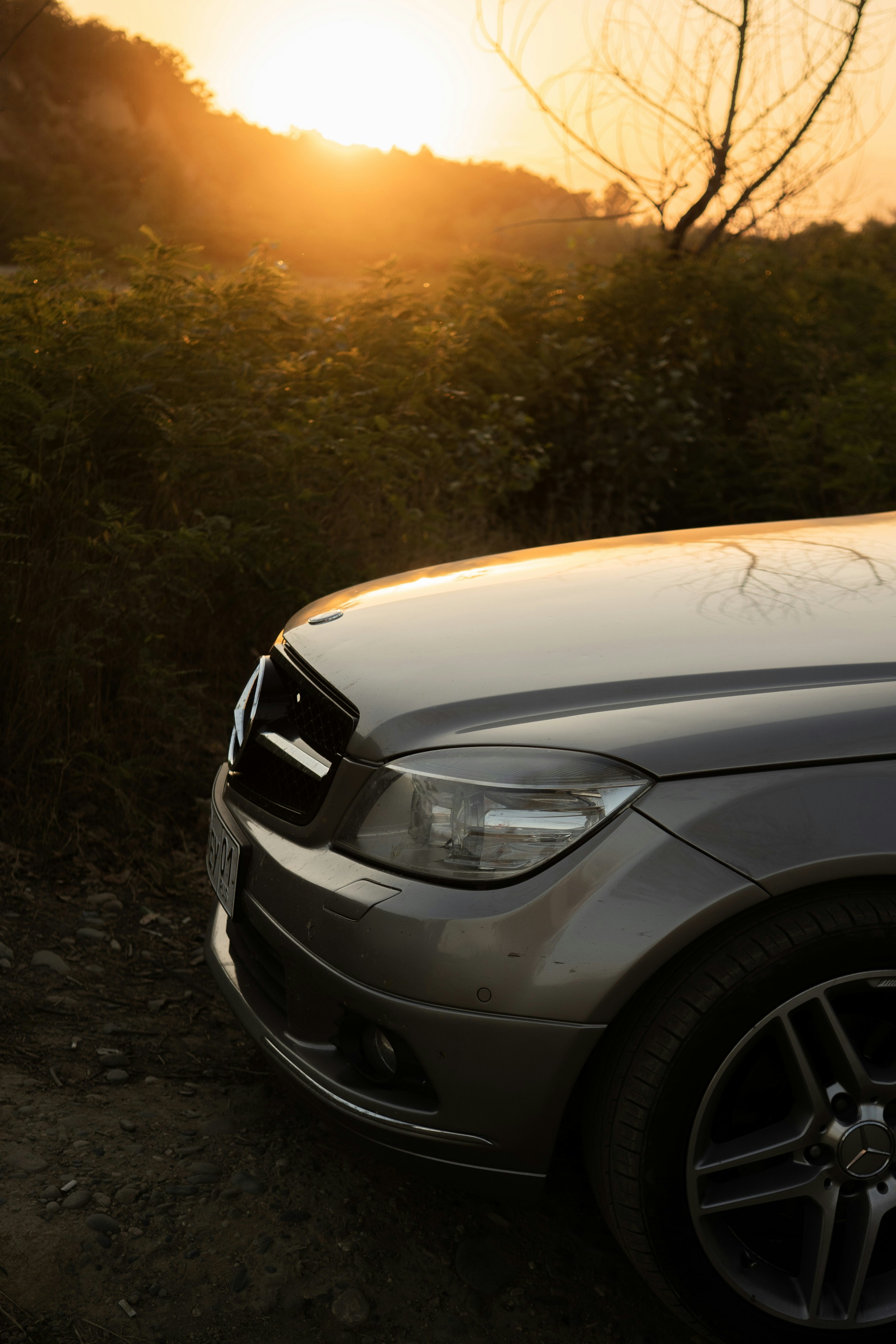 Auto argentata parcheggiata su strada sterrata al tramonto