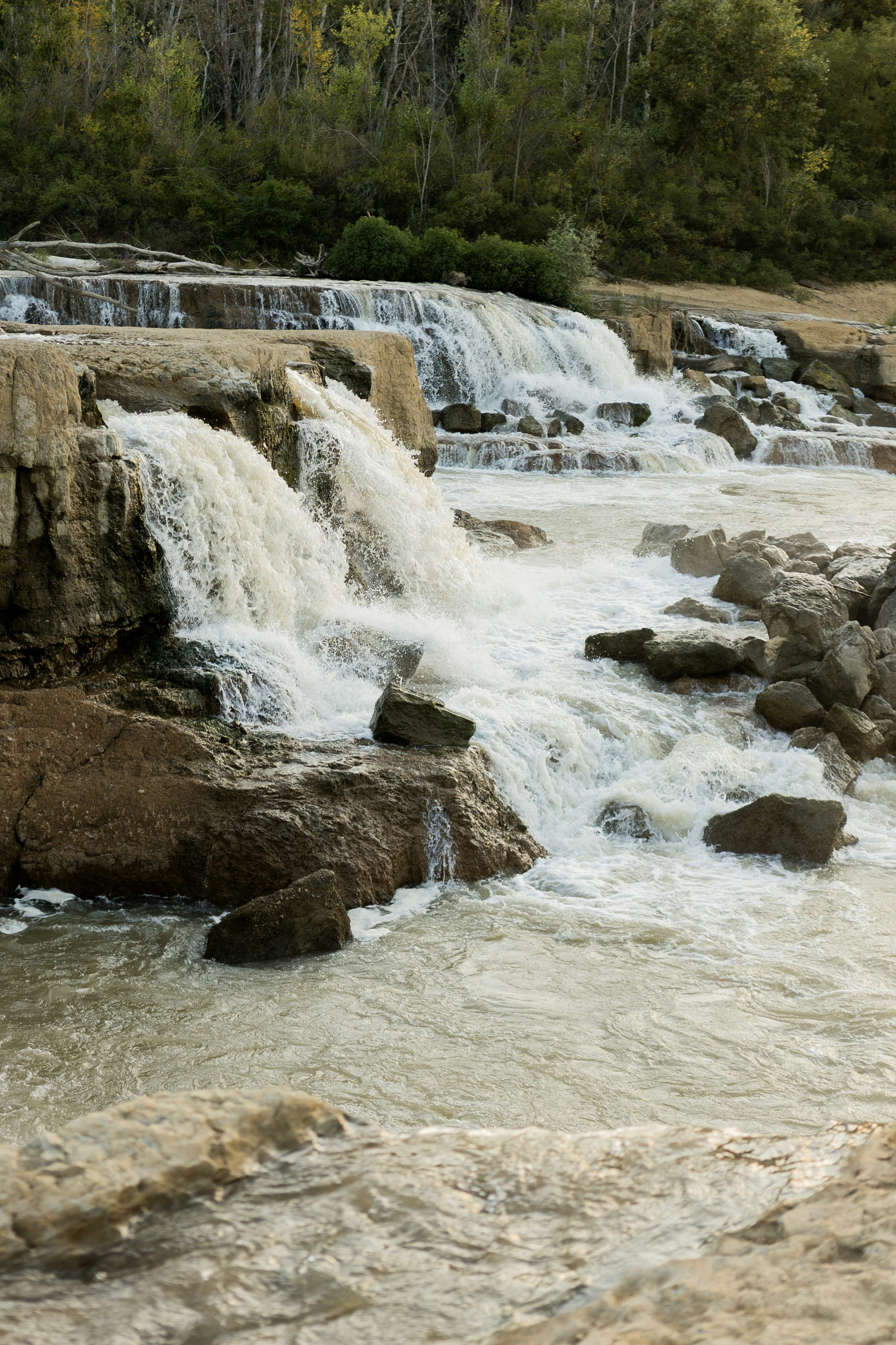 L'acqua scende a cascata su sporgenze rocciose in un ambiente naturale.
