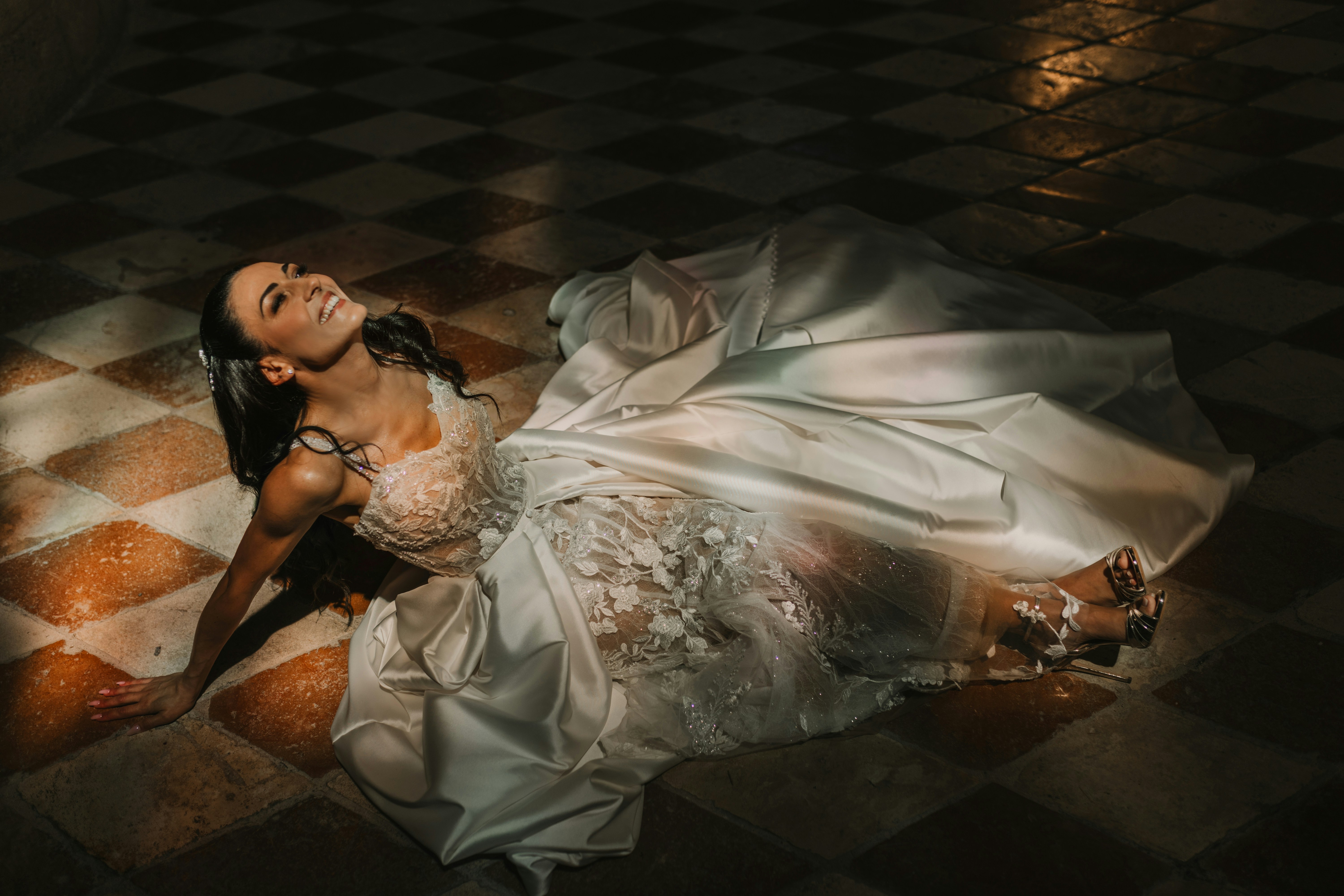 Bride in a white dress lying on a checkered floor.