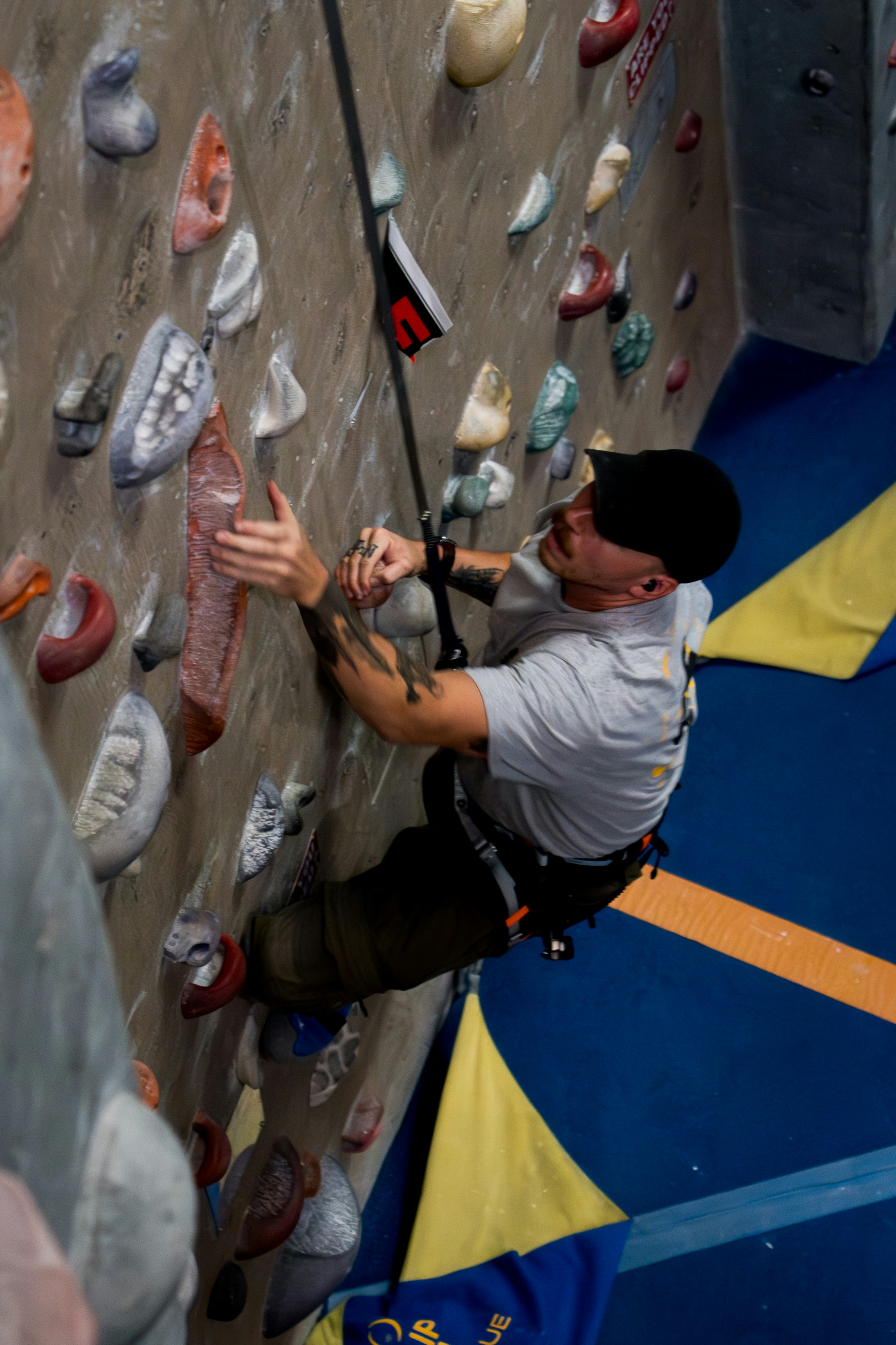 Man climbing indoor rock wall with safety rope
