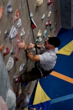 Man climbing indoor rock wall with safety rope
