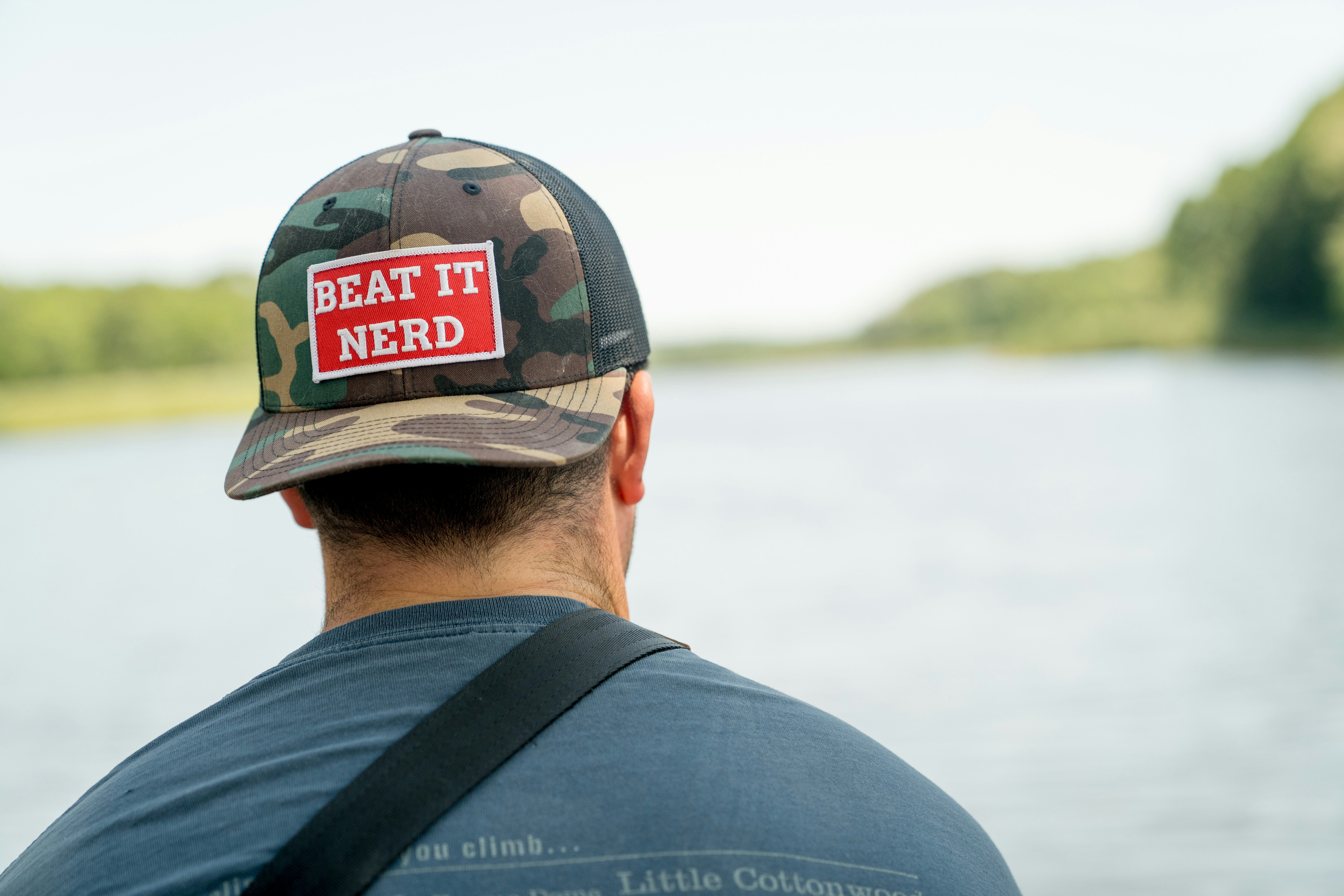Man wearing a camouflage hat looking at a lake