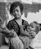 Young girl carries a sleeping baby