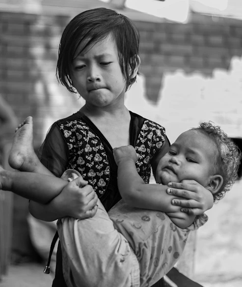 Young girl carries a sleeping baby