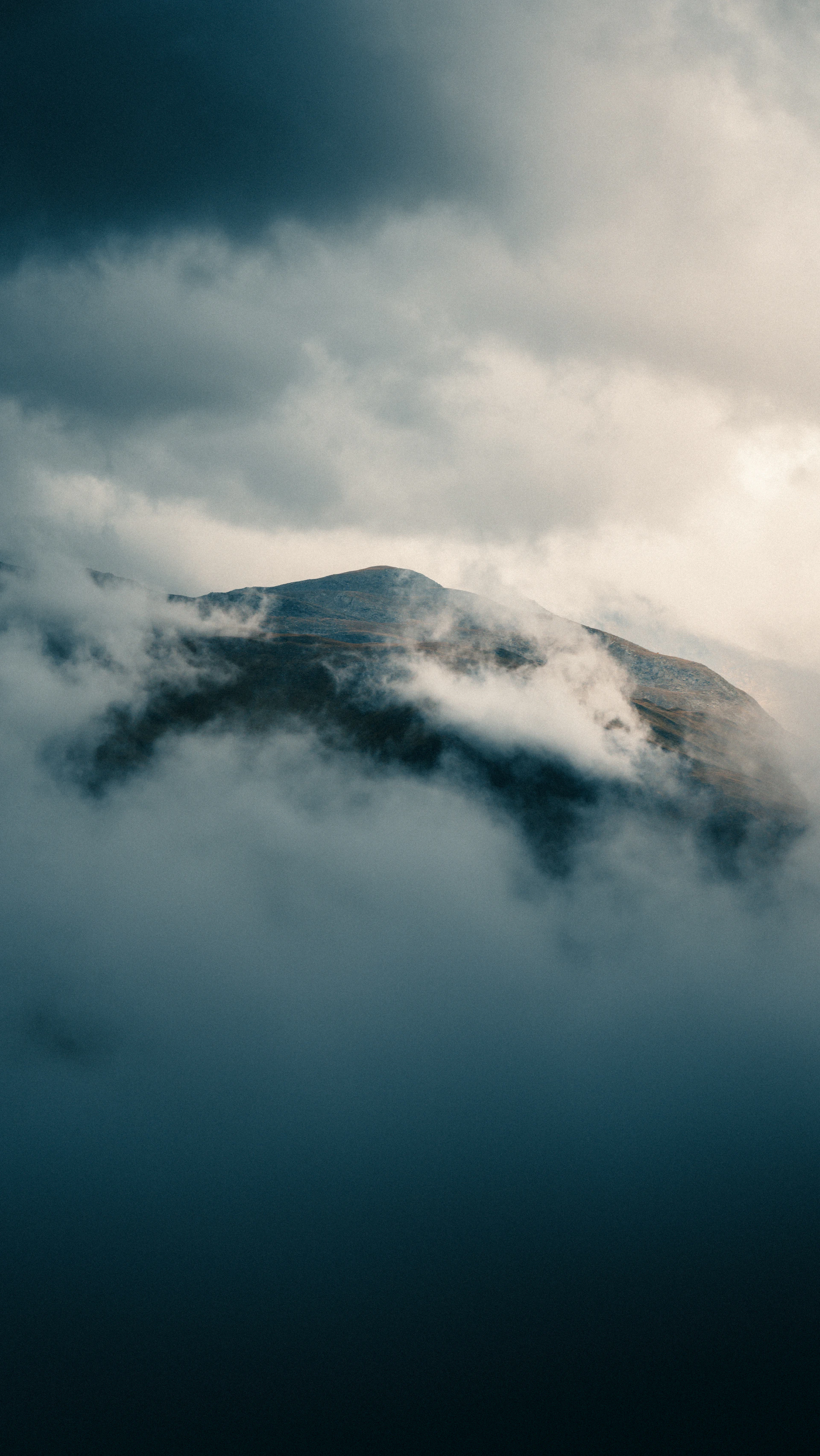 Mountain peak shrouded in dramatic clouds and fog.