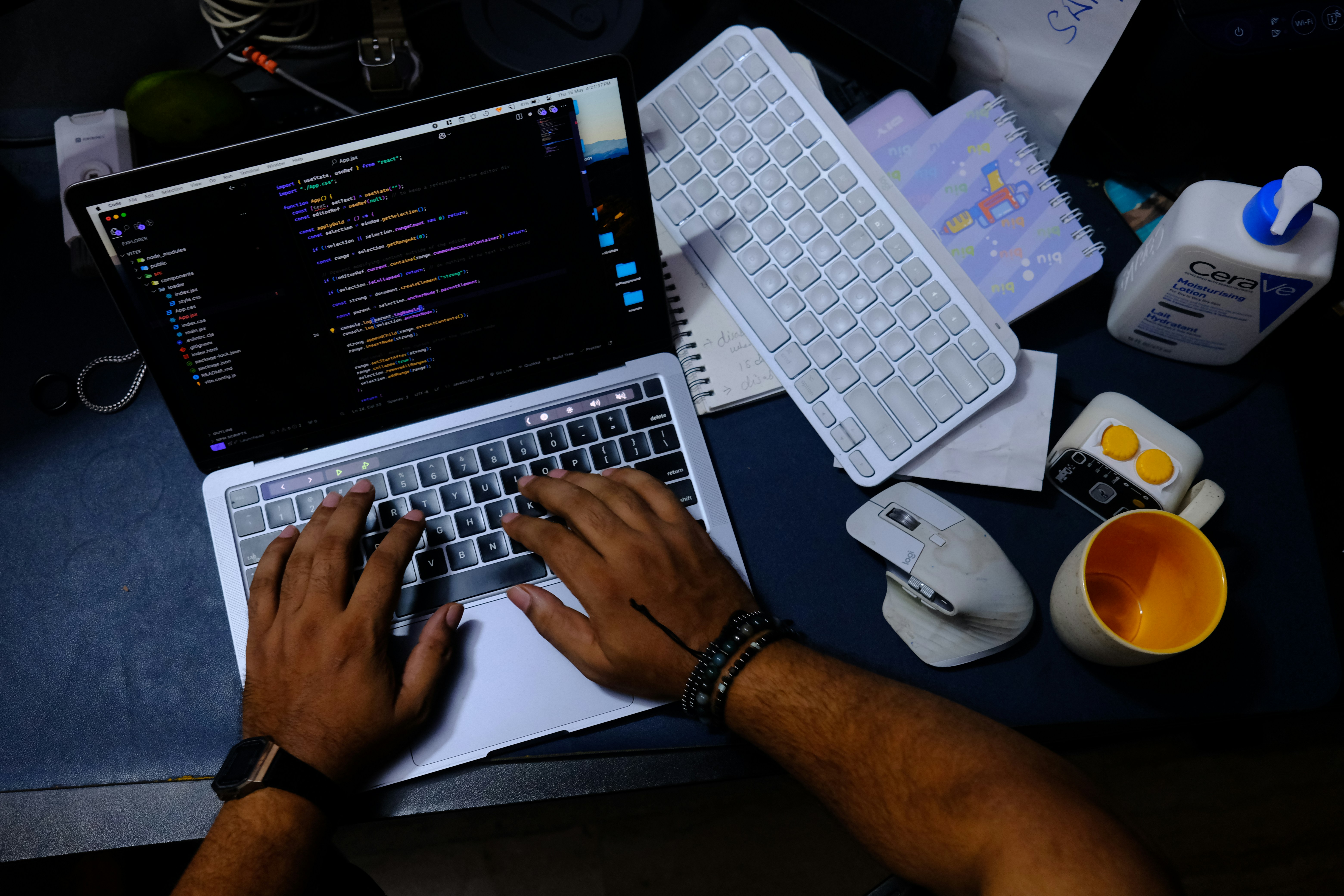 Hands typing on a laptop with code on screen.