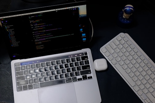 Laptop and keyboard on a dark desk
