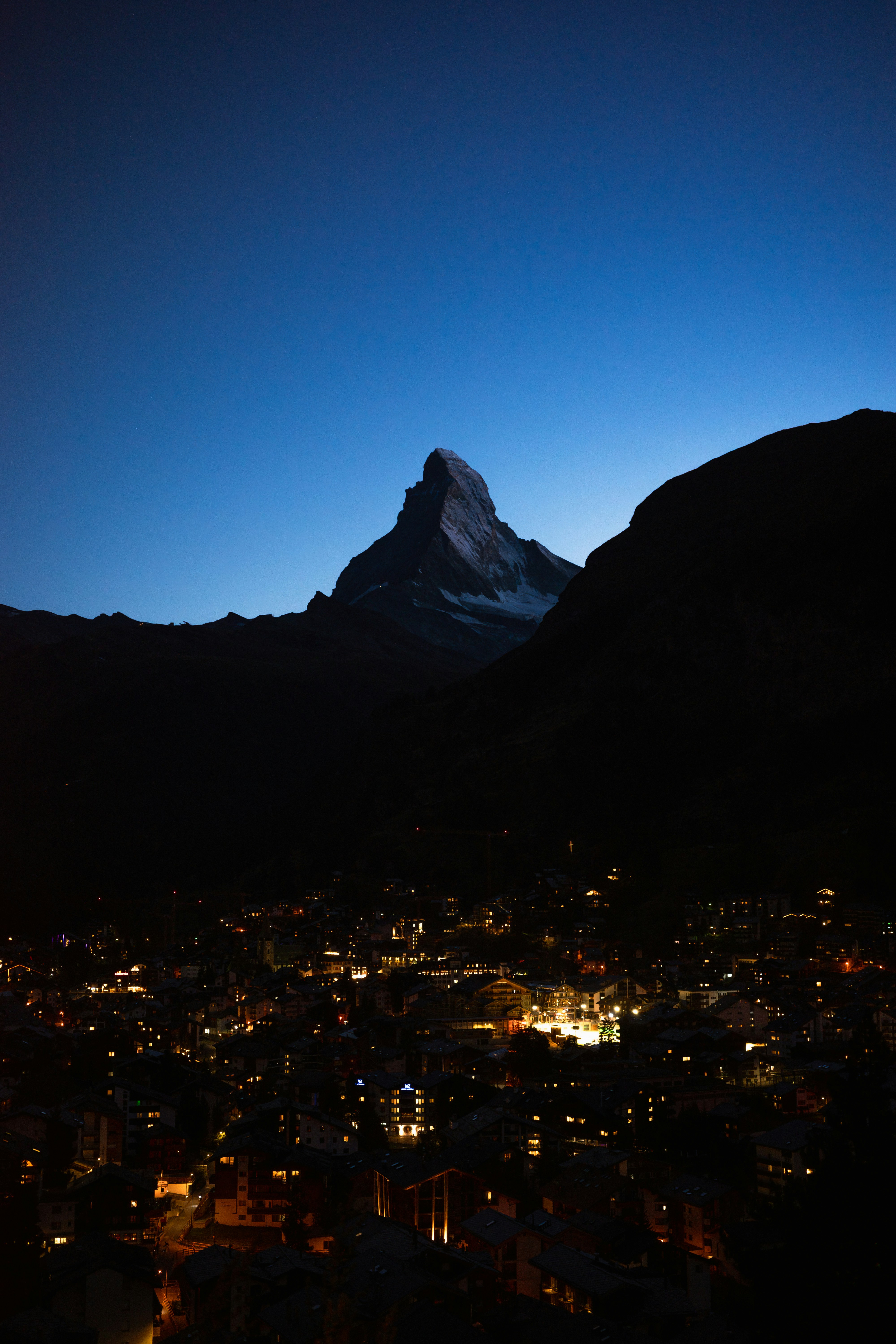 Mountain peak illuminated by city lights at dusk