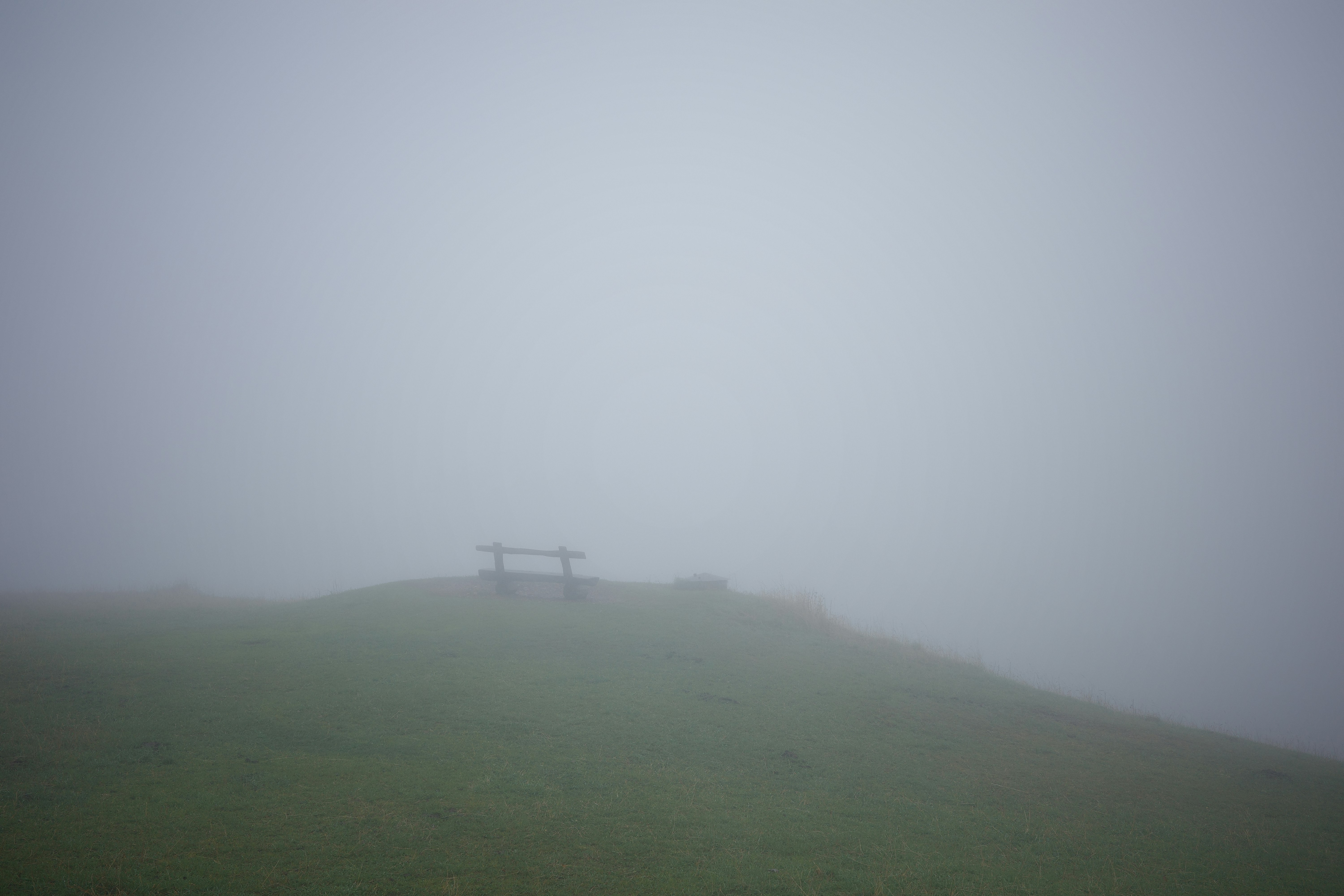 Bench on a foggy grassy hill