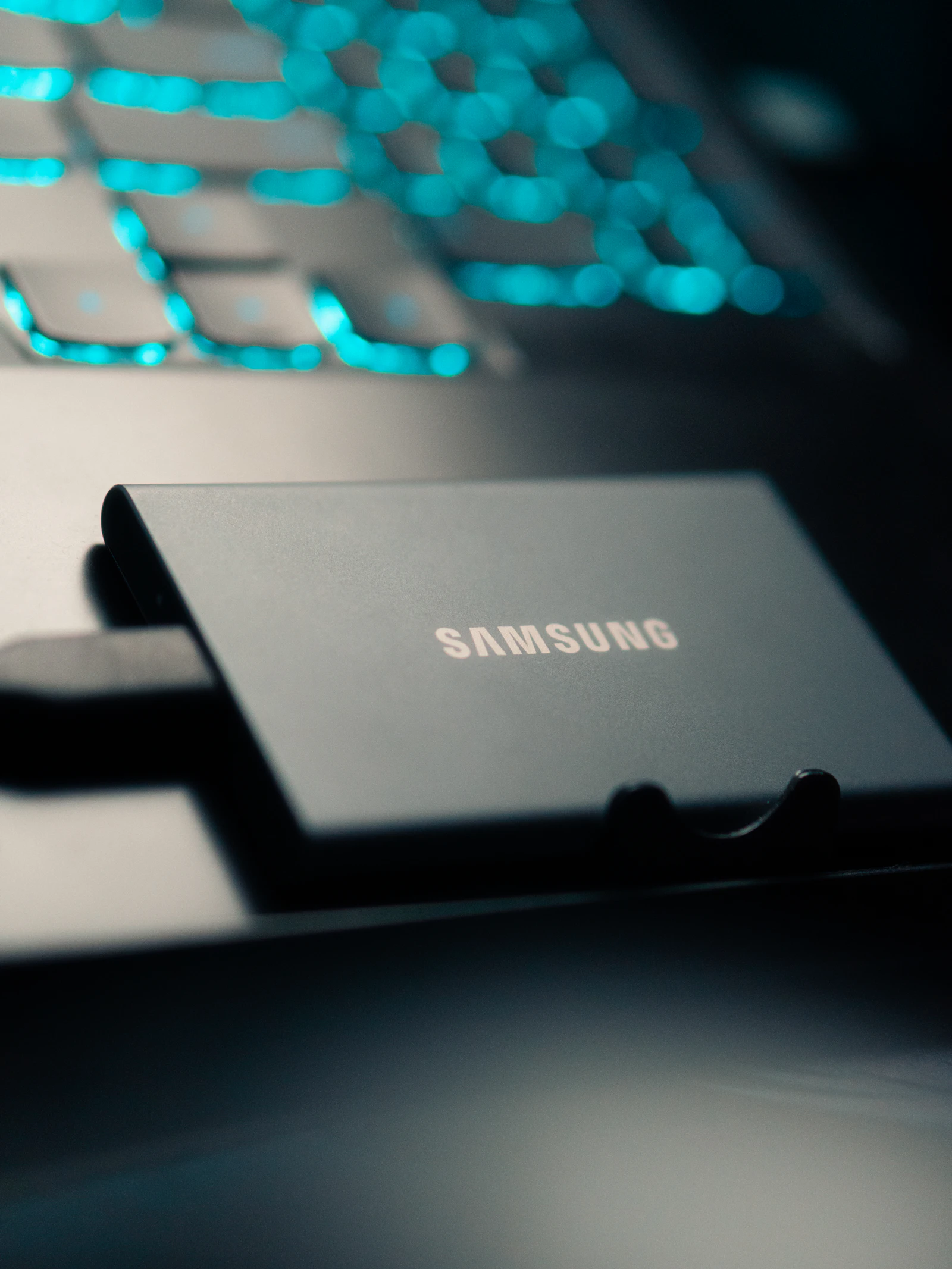 Portable SSD on a desk next to a backlit keyboard, the kind of spare drive an M.2 enclosure puts back to work
