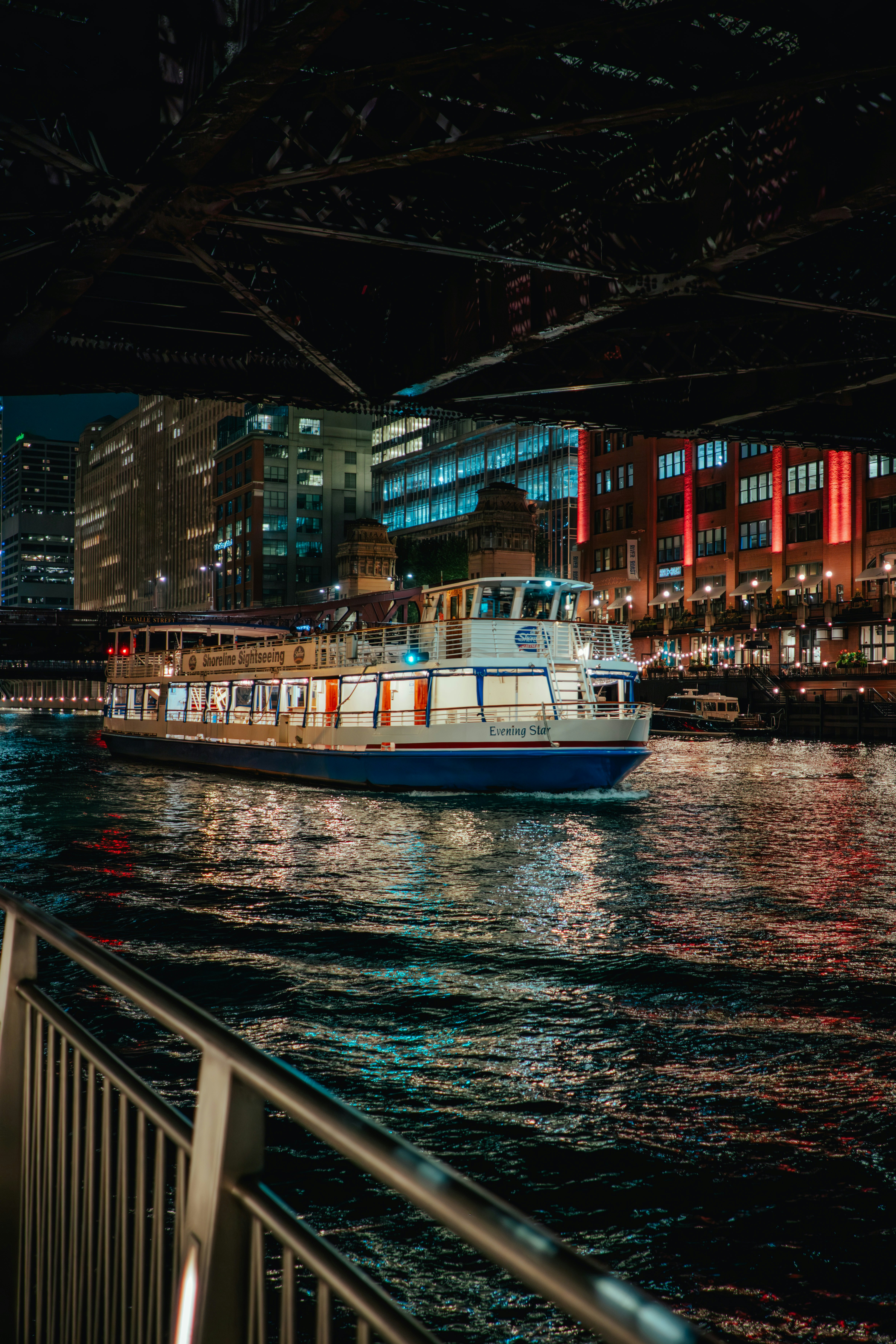 A boat travels on a river at night.