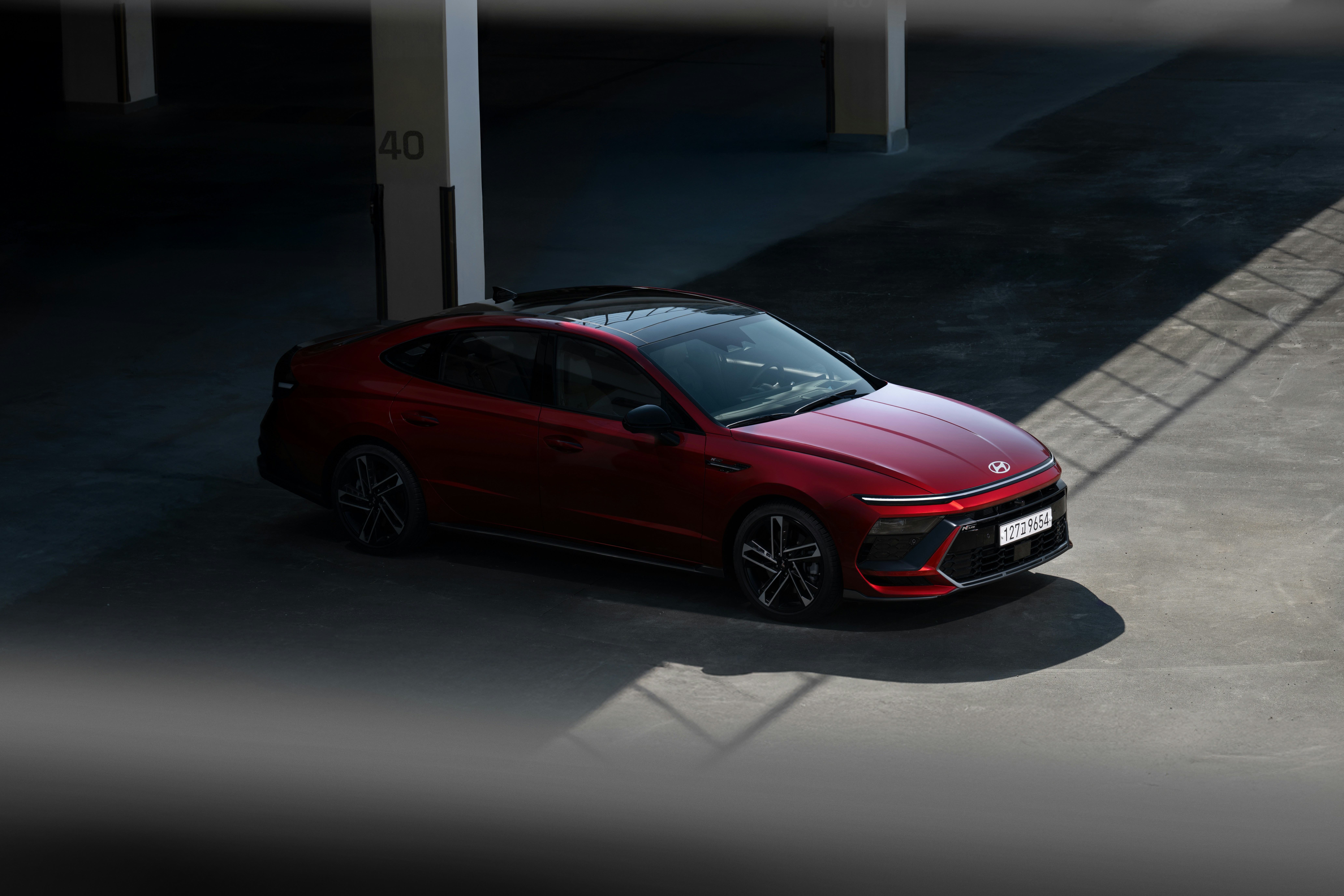 Red sedan parked in a dimly lit garage.