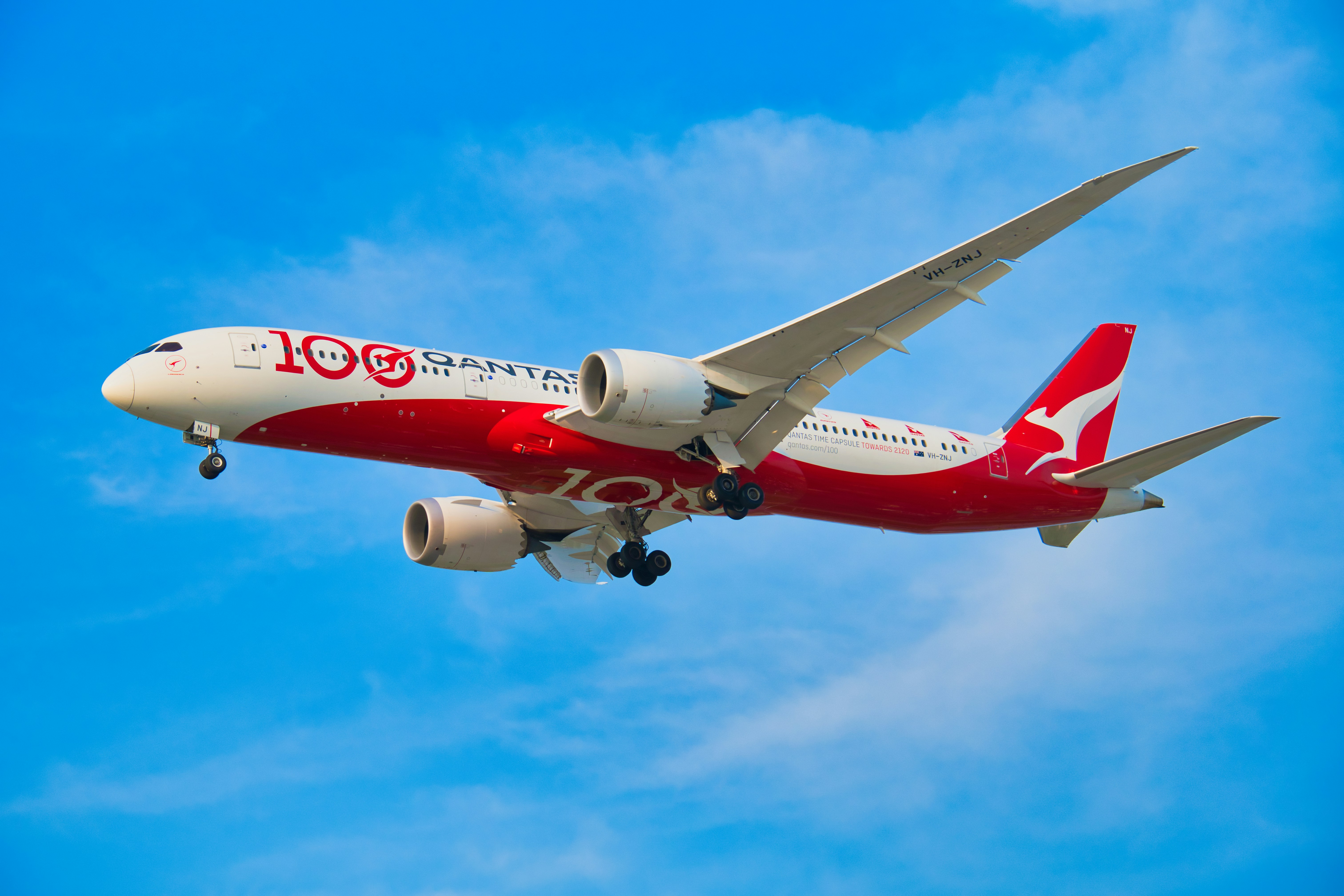 Ein Qantas-Flugzeug, das in strahlend blauem Himmel fliegt.