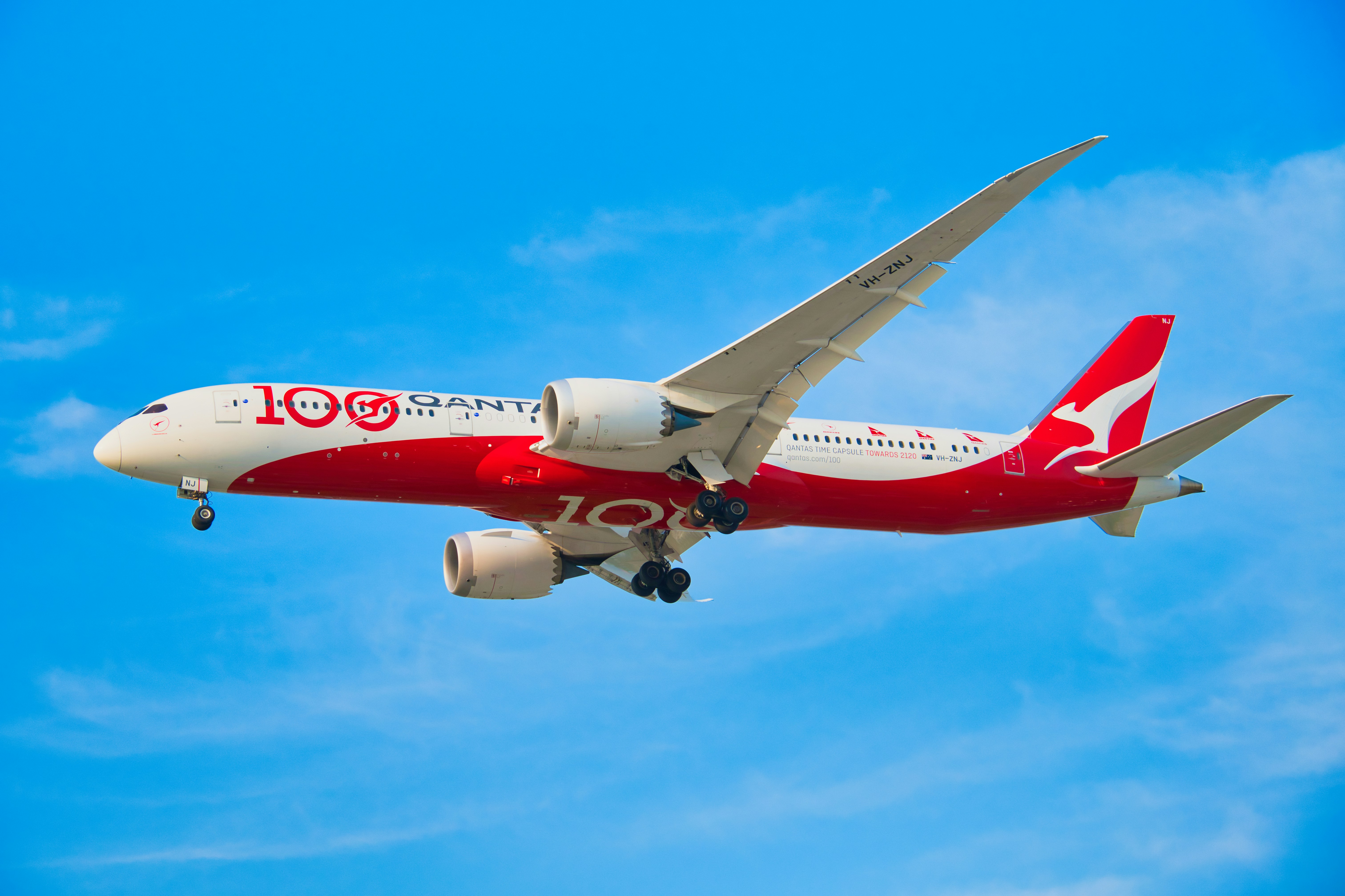 Ein Qantas-Flugzeug, das in strahlend blauem Himmel fliegt.