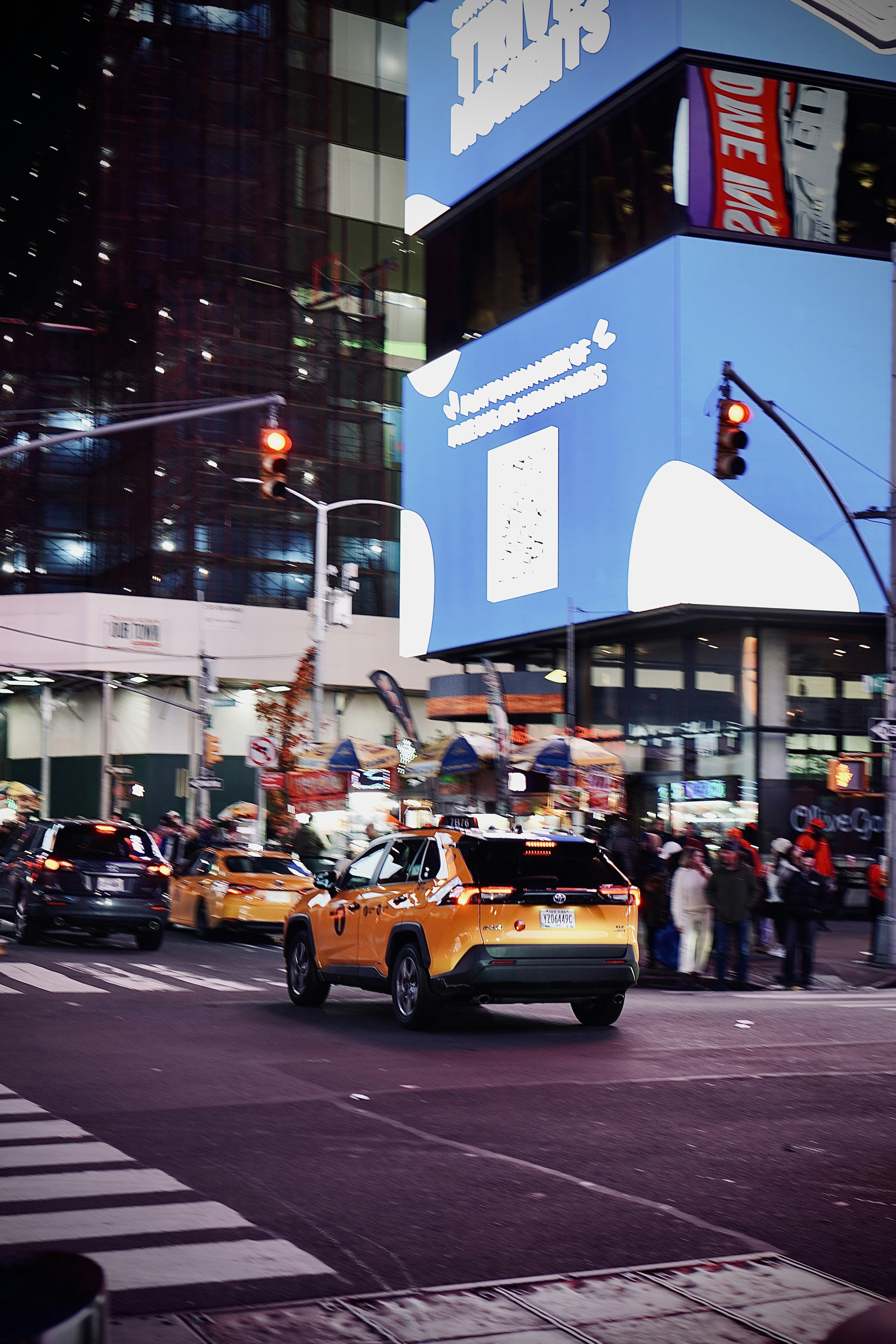 Yellow taxis on a busy city street at night.
