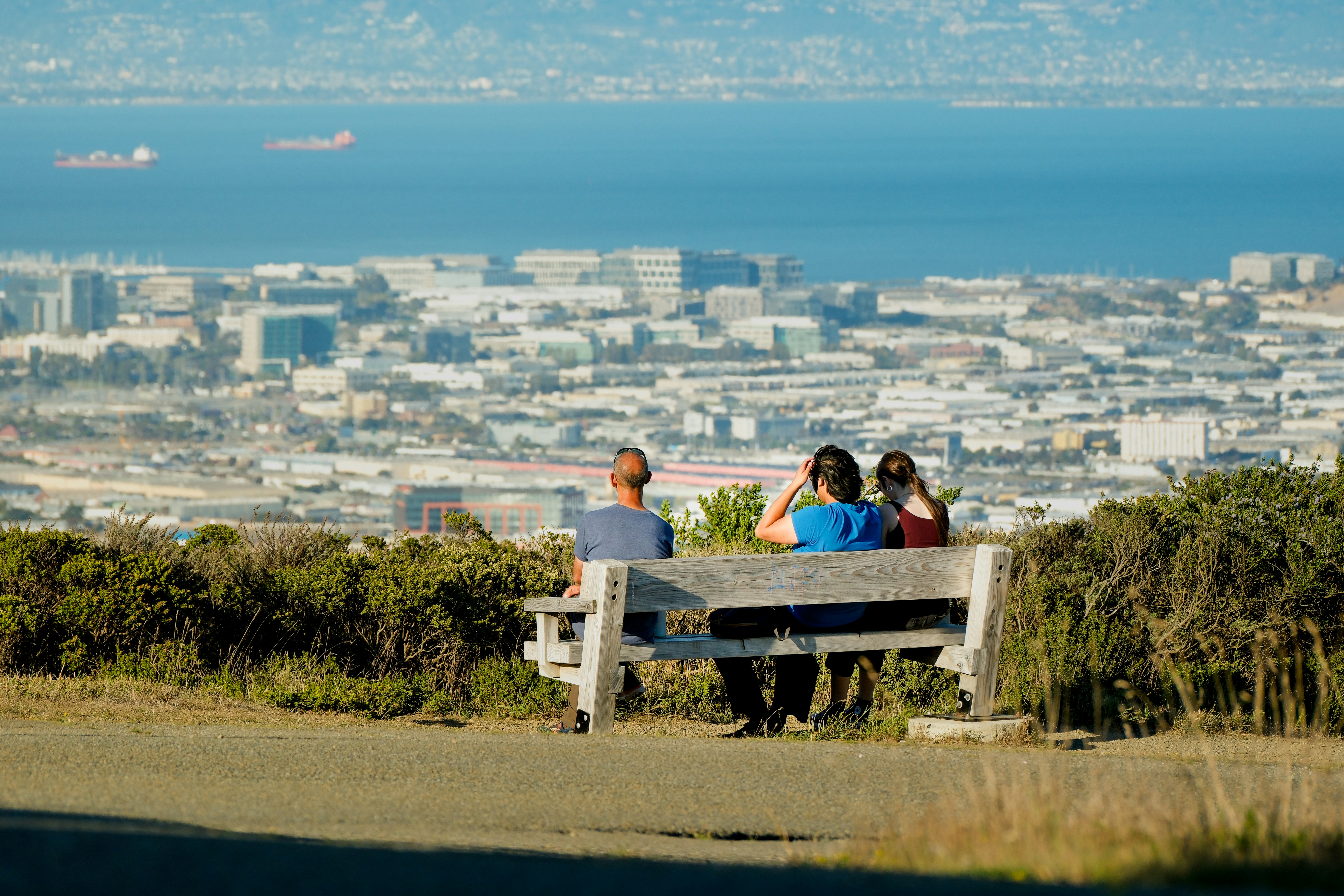 Two people sitting on a bench overlooking a Peninsula city and the bay near San Bruno