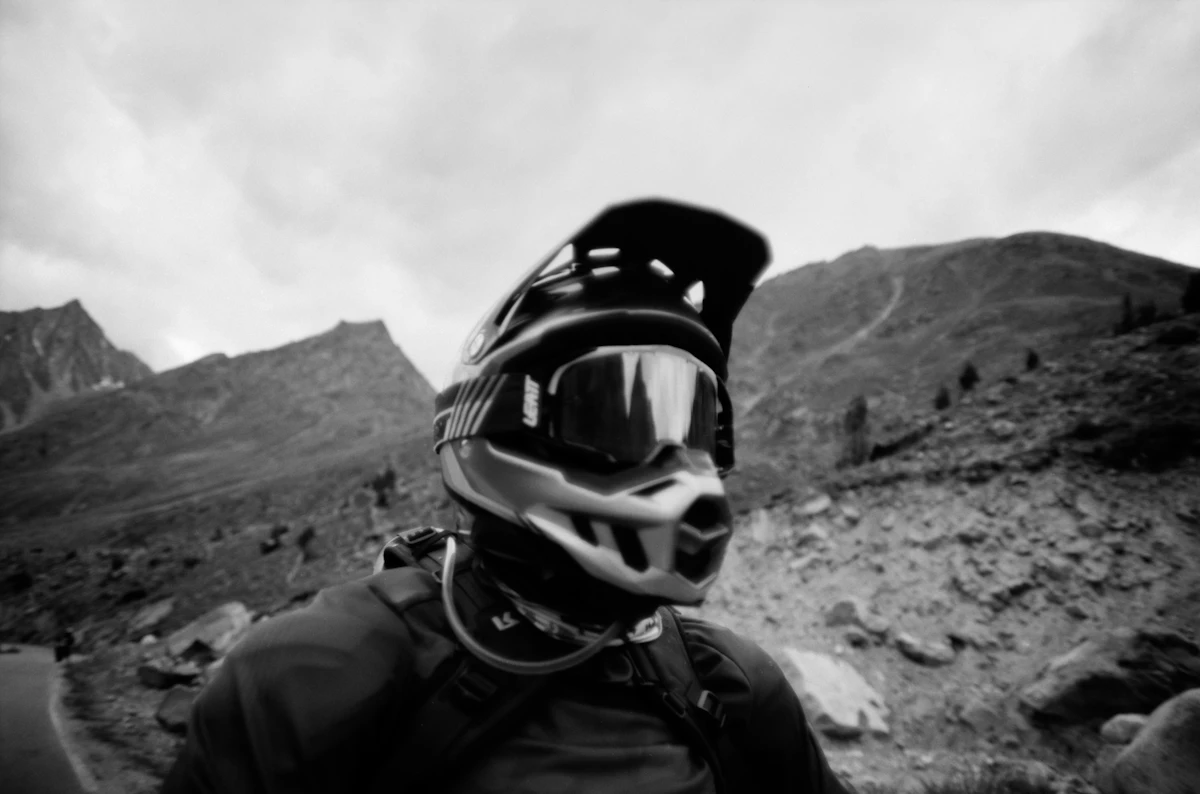 Man in a helmet and goggles on a mountain trail.