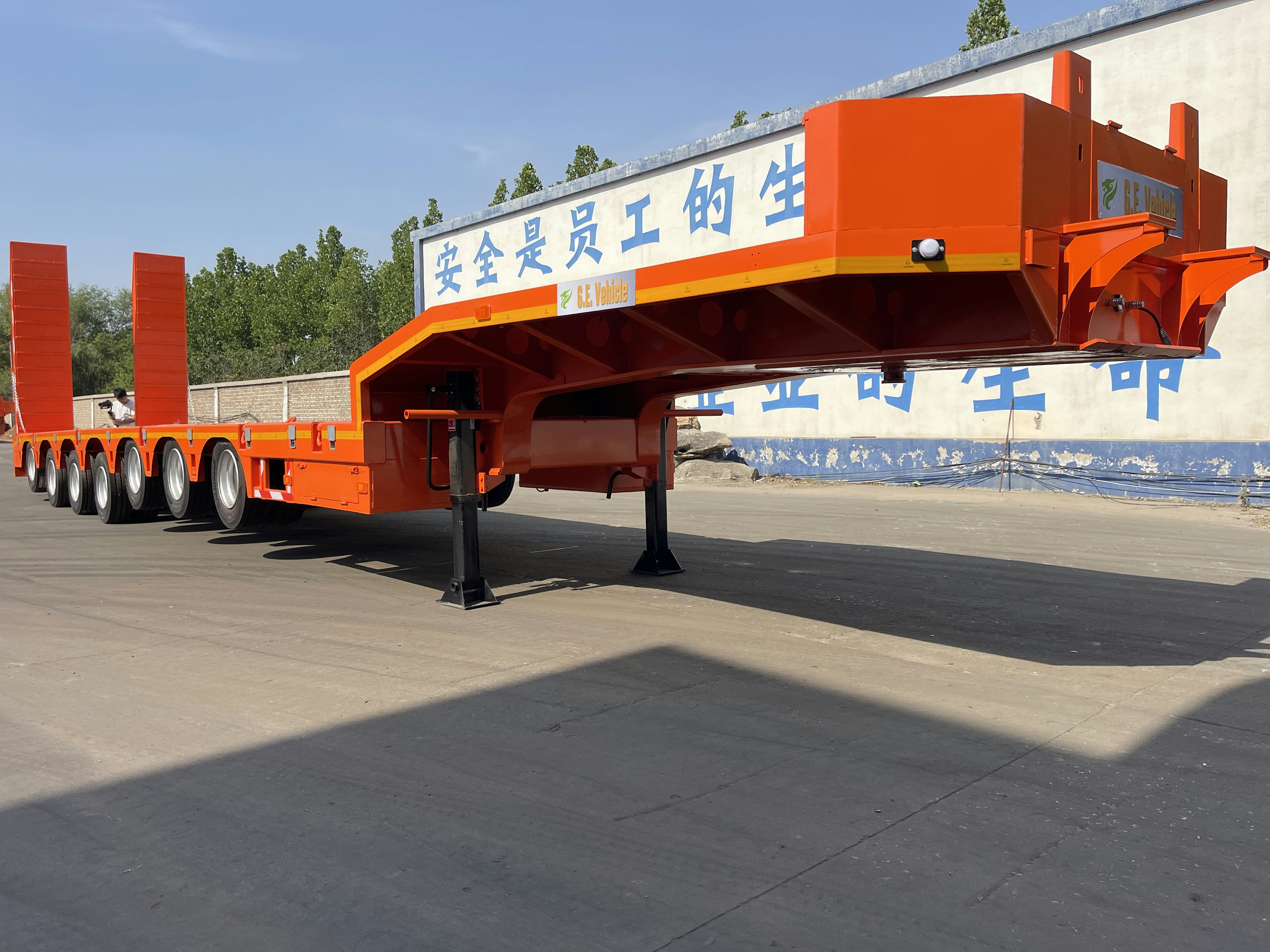 An orange heavy-duty trailer with multiple axles.