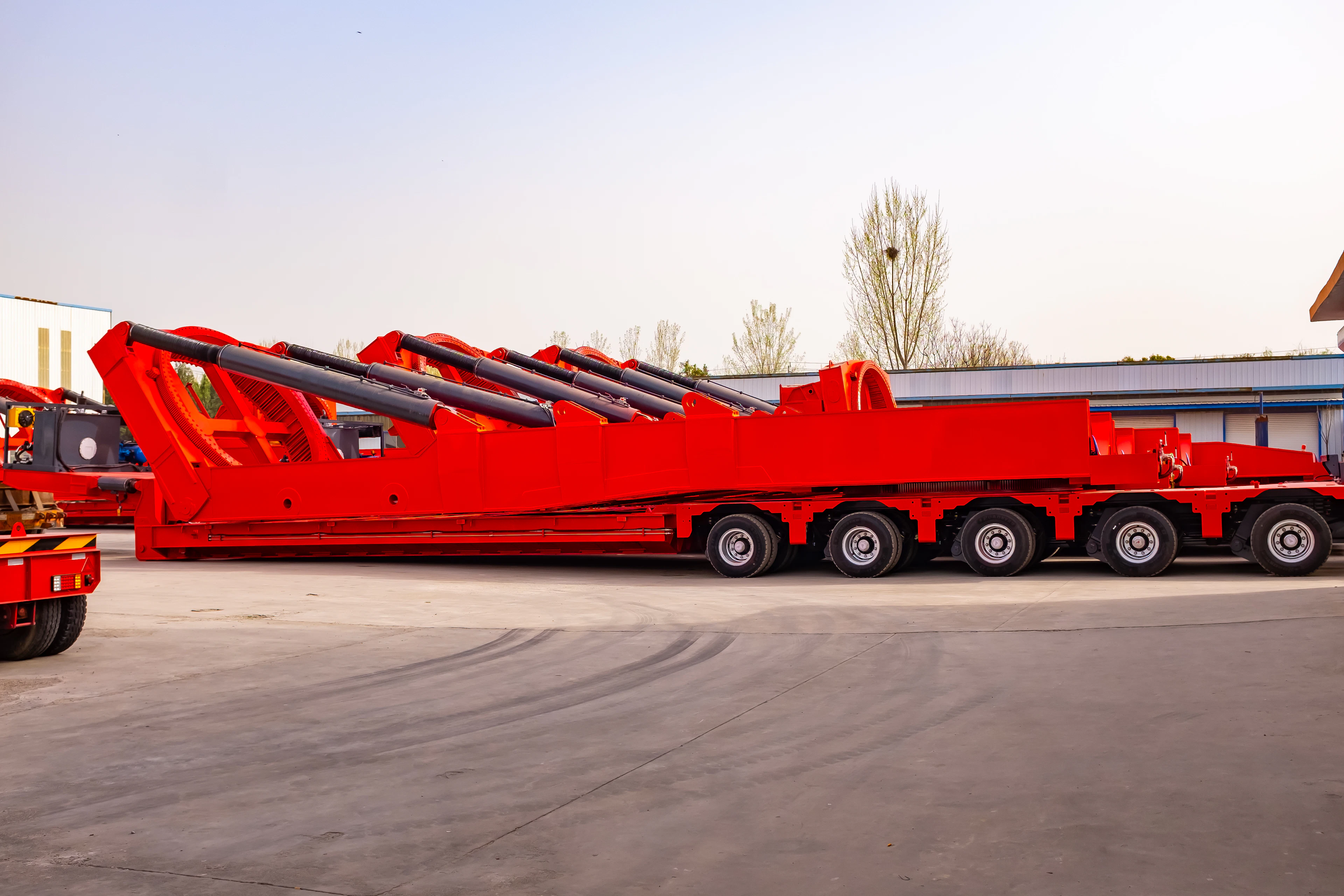 A row of red multi-axle heavy-haul trailers