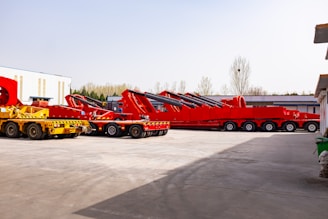Several heavy-duty red and yellow transport vehicles parked outdoors.