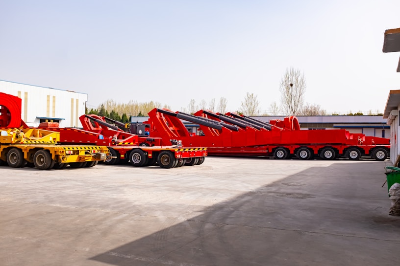 Several heavy-duty red and yellow transport vehicles parked outdoors.