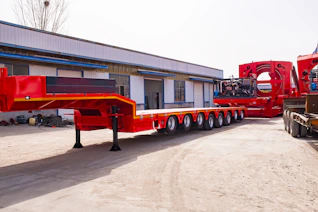 A long red trailer with many wheels