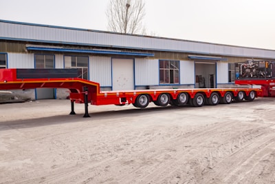 Red heavy-duty multi-axle trailer parked outside building