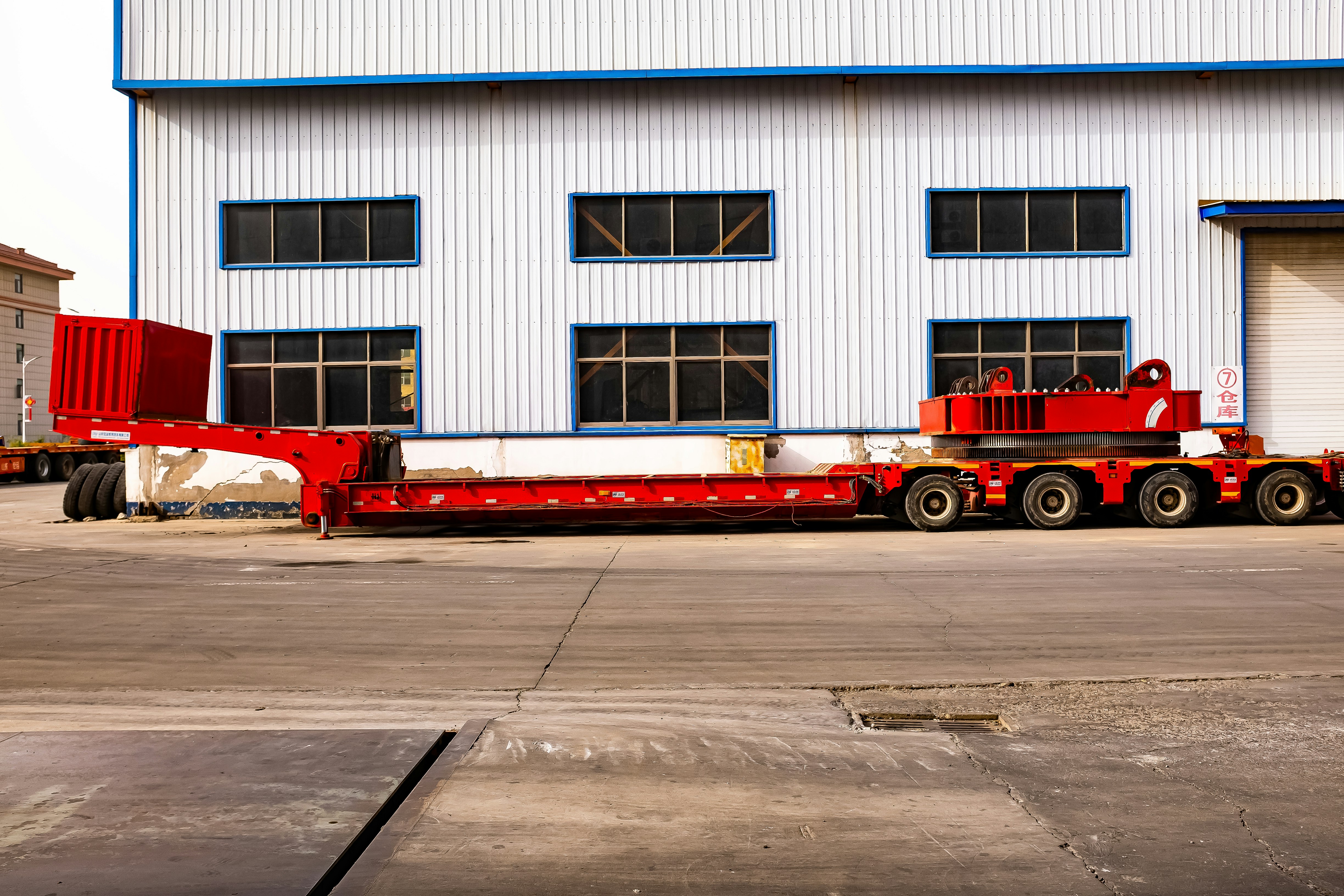 Heavy machinery trailer parked outside industrial building