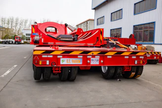 Red heavy-duty trailer with multiple wheels.