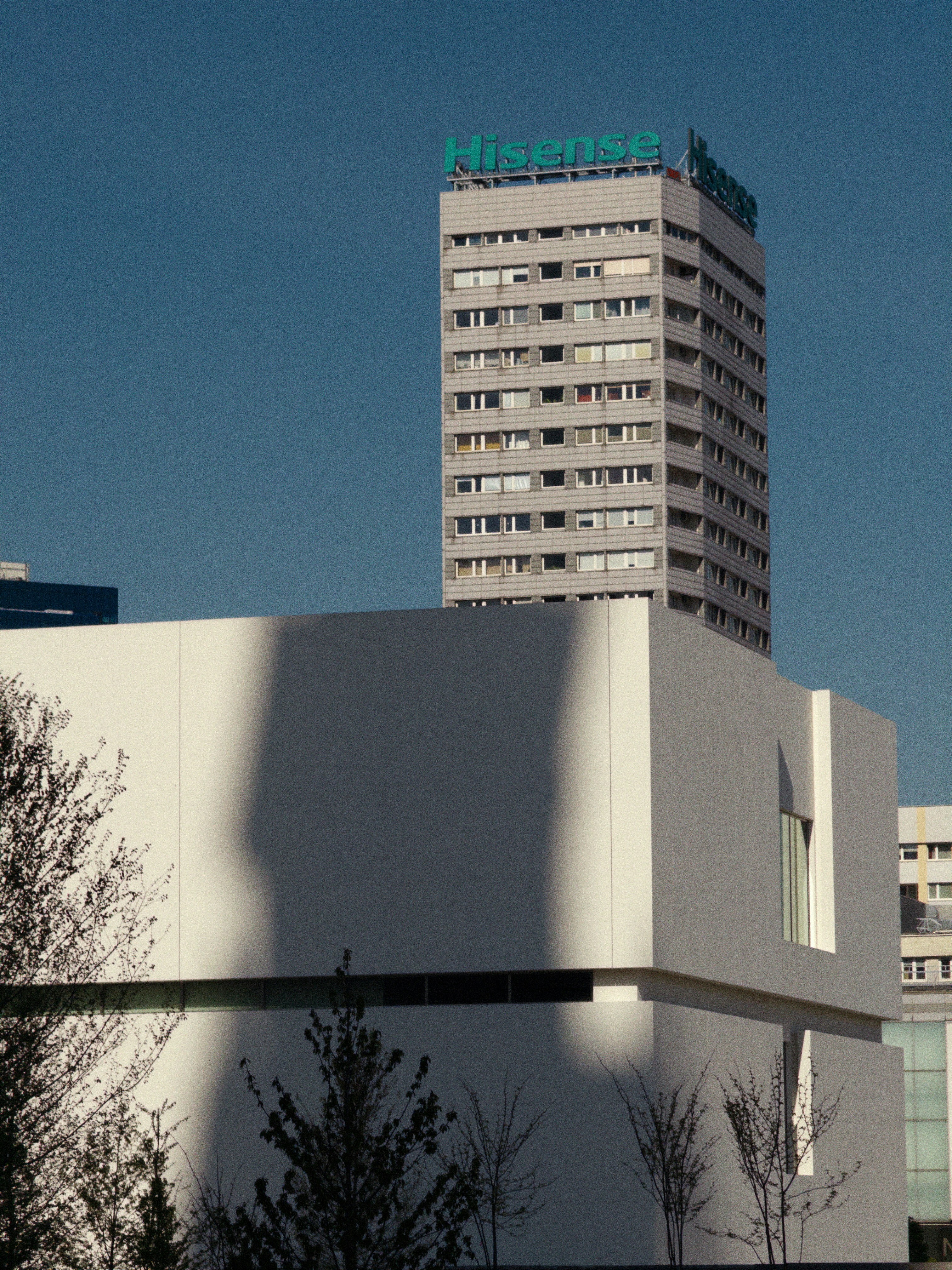 Modern white building with tall skyscraper behind