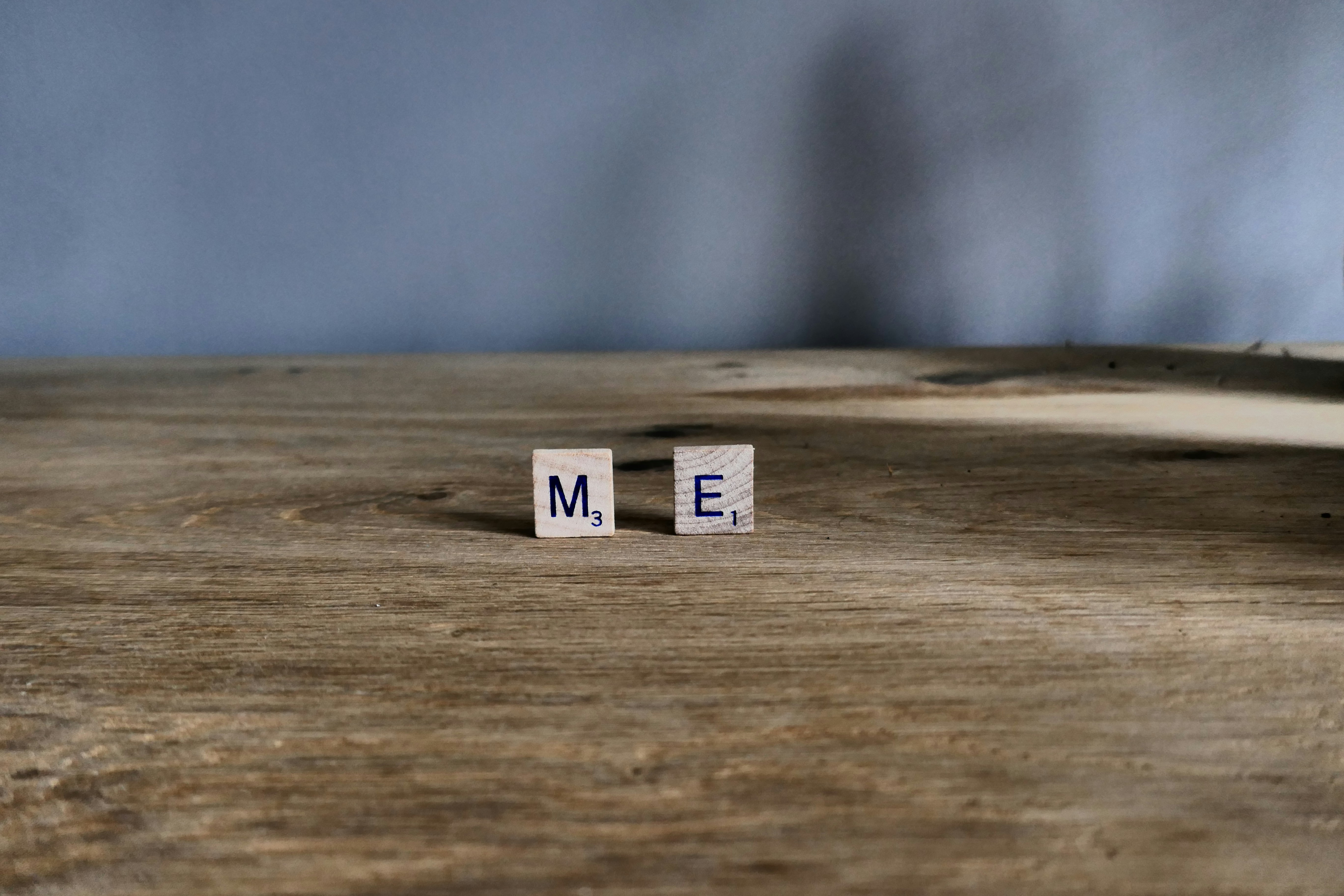 Las fichas de Scrabble me deletrean en la superficie de madera