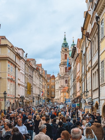 Crowded street with historic buildings and church spire.