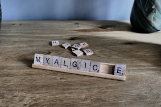 Scrabble tiles spell 'myalgic' on wooden surface