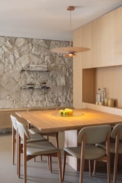 Modern dining room with stone accent wall and wooden table.