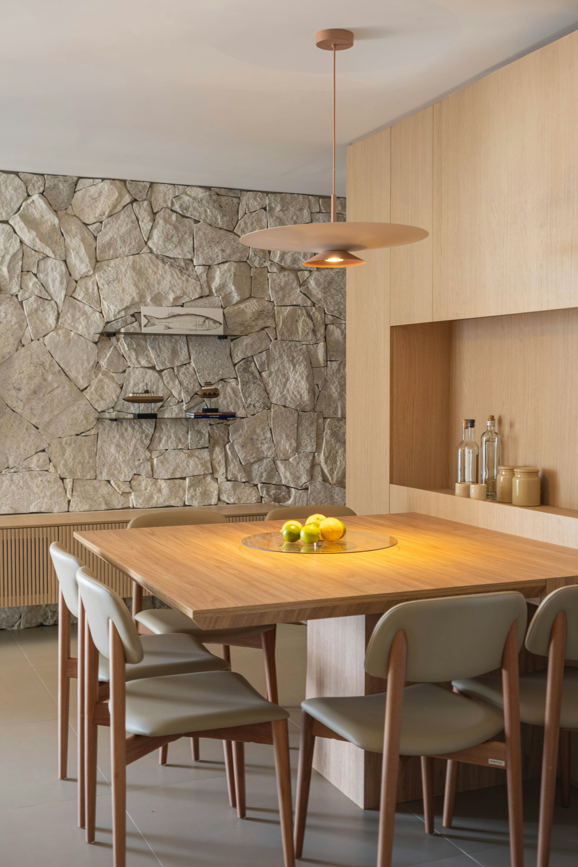 Modern dining room with stone accent wall and wooden table.