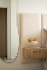 A modern bedroom with a floating nightstand and vase.