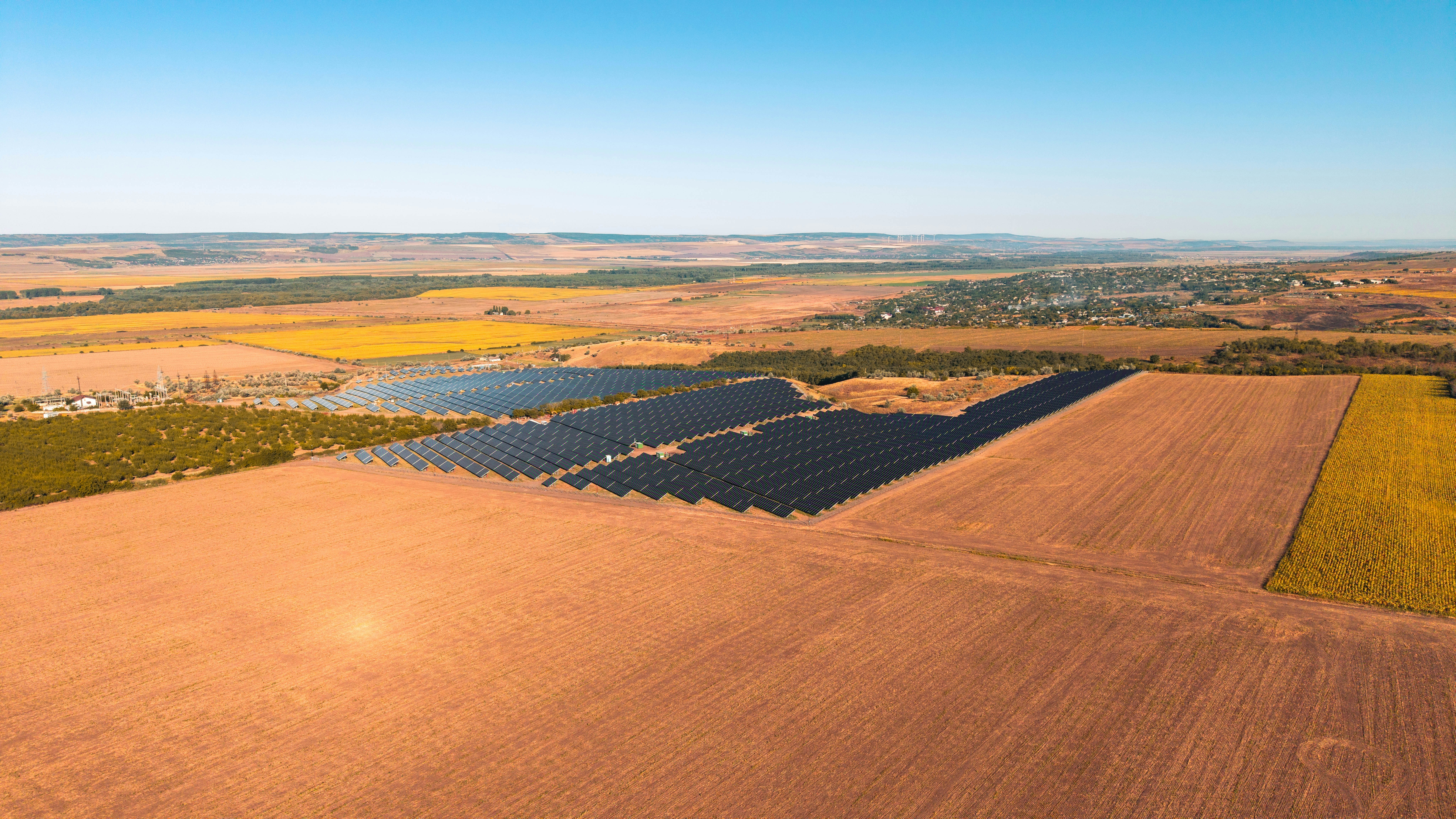 Solar panels in a vast field under a clear sky.