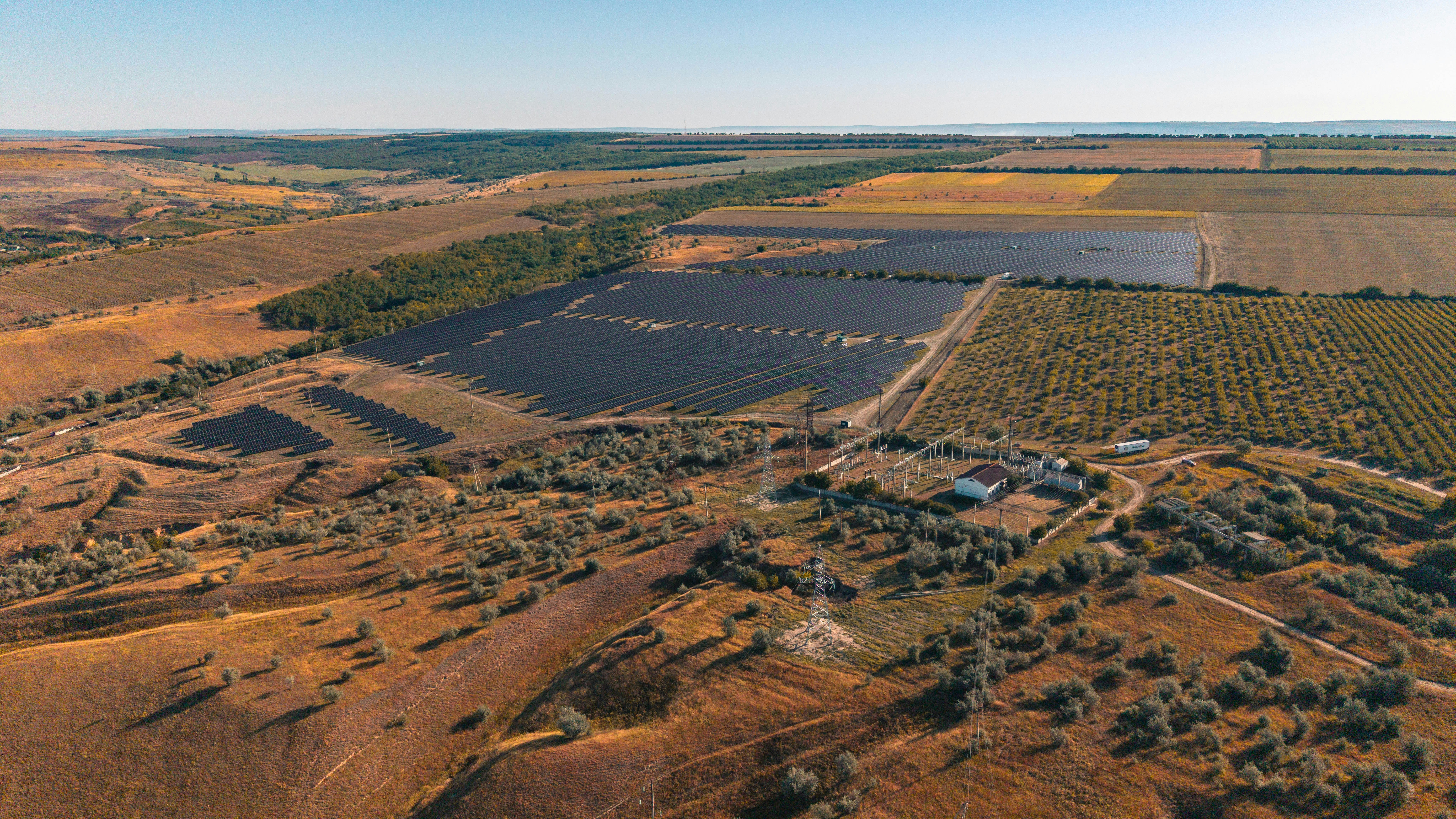 Solar farm in a rural landscape under a clear sky.