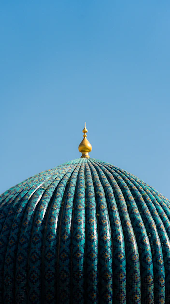 Turquoise dome with golden spire against blue sky