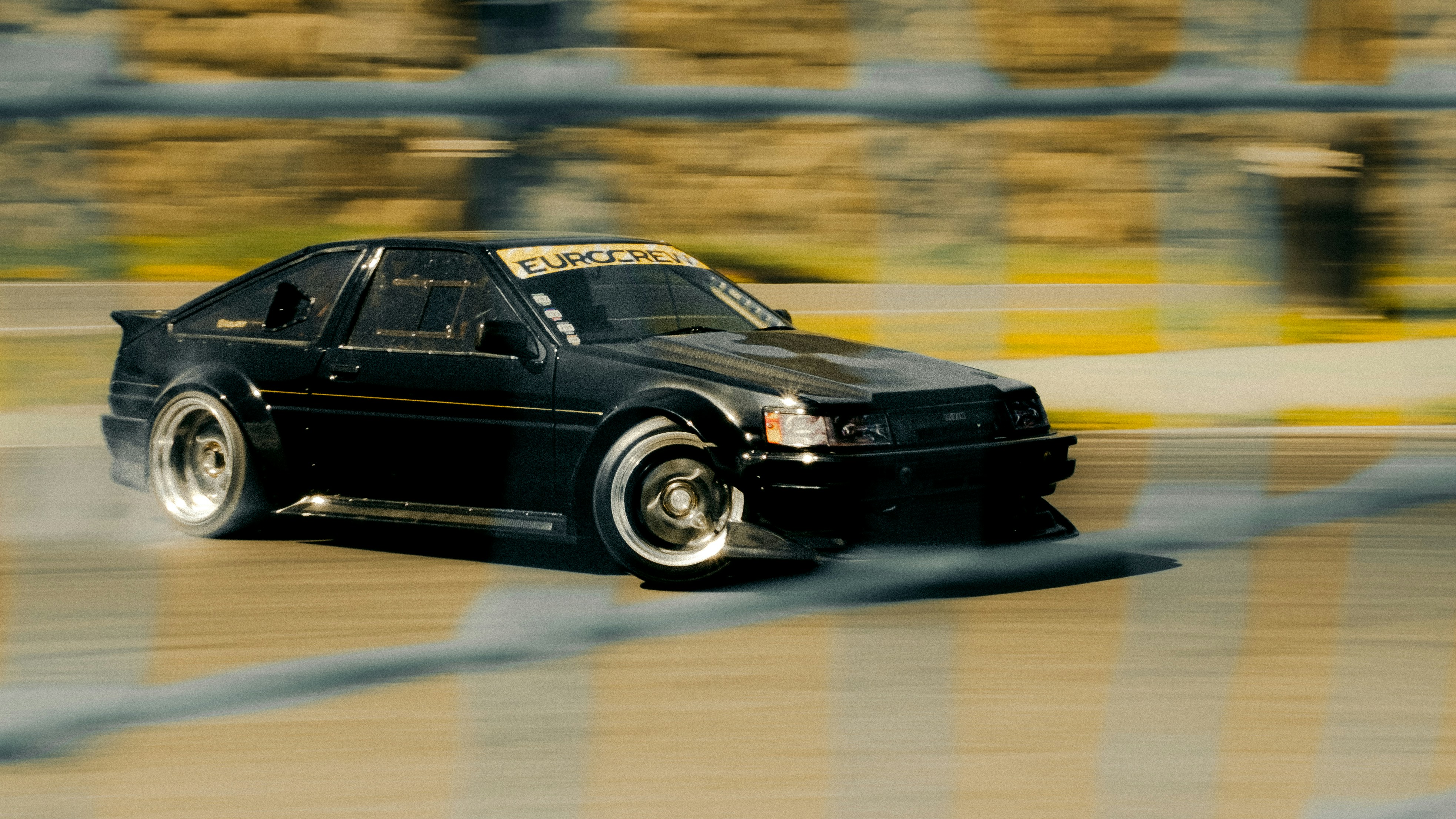 Black sports car drifting on a wet track.