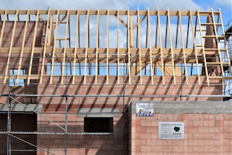 Building under construction with wooden roof trusses.